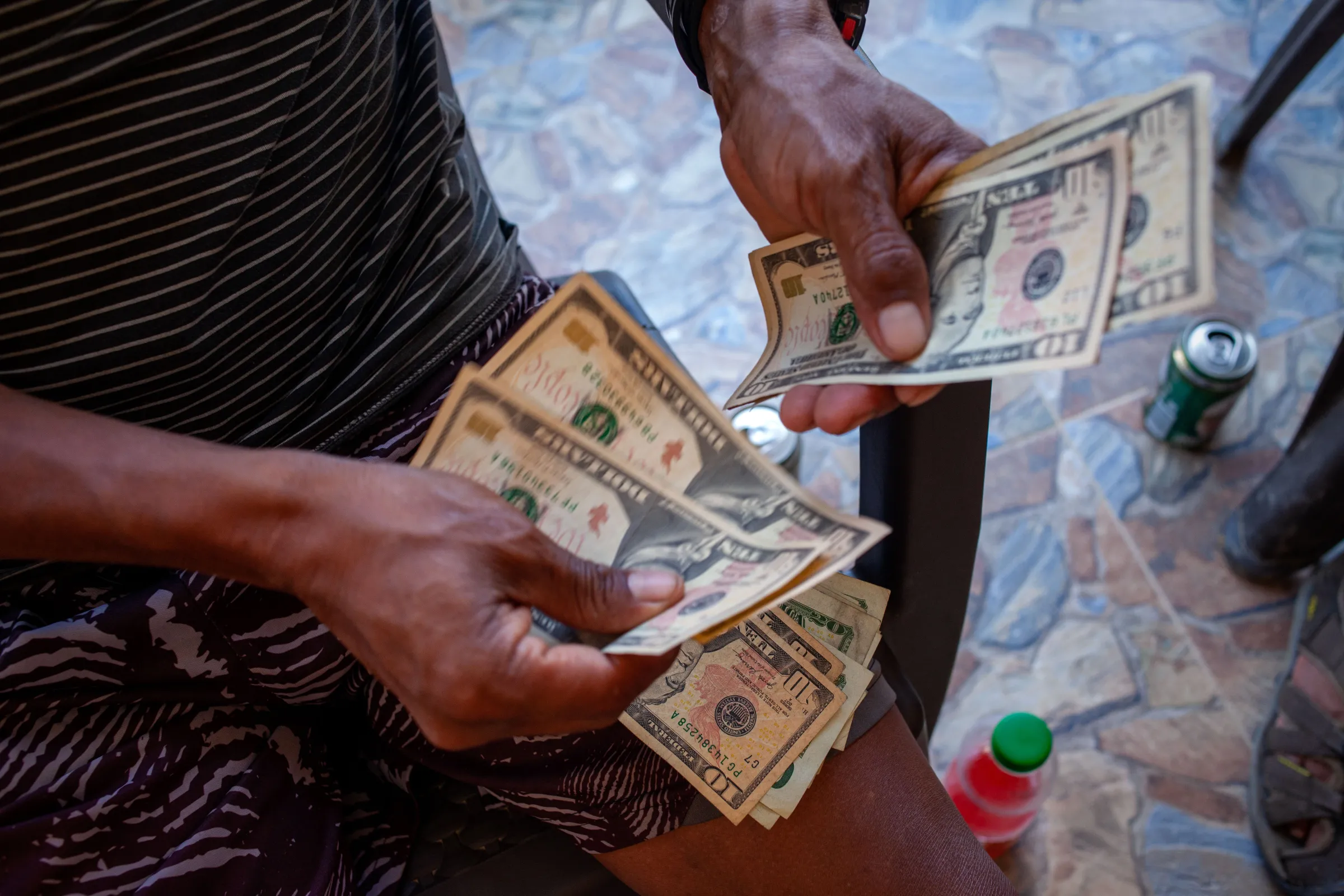 Colombian Carlos Alberto Ballesteros, an elected community and guide leader, hands out dollar bills to several Panamanian indigenous leaders on the porch of his home in the Colombian town of Capurganá. Indigenous leaders receive a share of guide fees for each migrant who passes through their territory. Capurganá, Colombia, July 26, 2022. Thomson Reuters Foundation/Fabio Cuttica