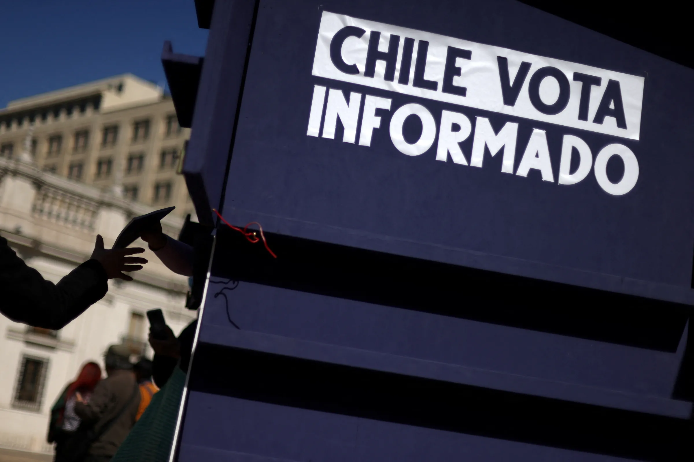 A slogan is seen as a citizen receives a copy of the proposed new Chilean constitution ahead of the upcoming September 4th constitutional referendum