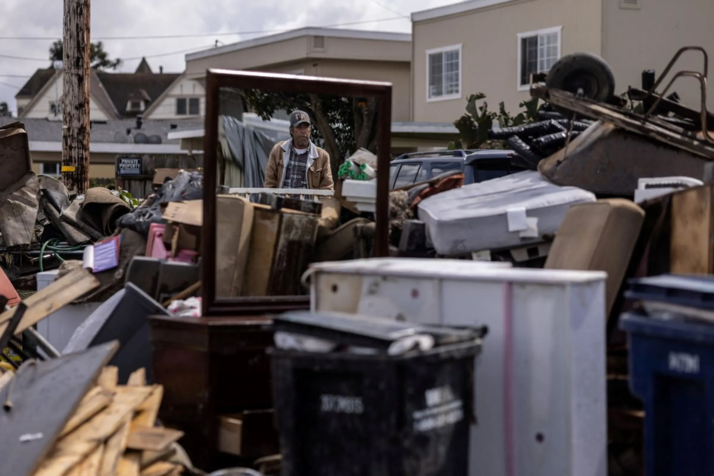 A man looks at a neighbor's damaged belongings after numerous rain storms flooded a residential area, in Pajaro, California, U.S., March 29, 2023. REUTERS/Carlos Barria