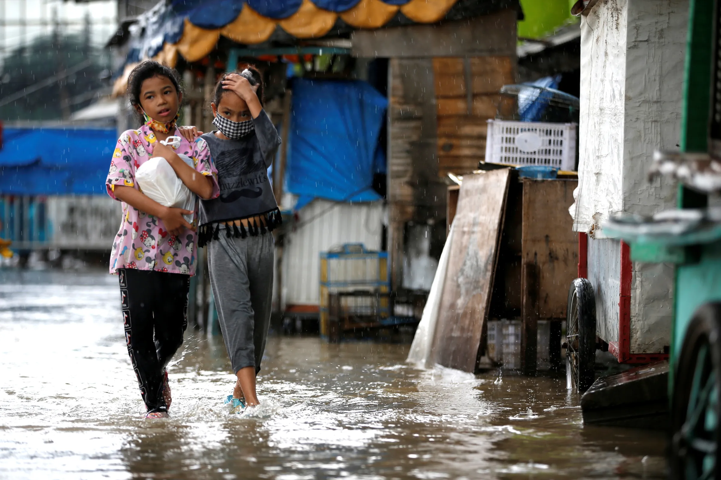 Girls walk along a street affected by floods in Jakarta, Indonesia