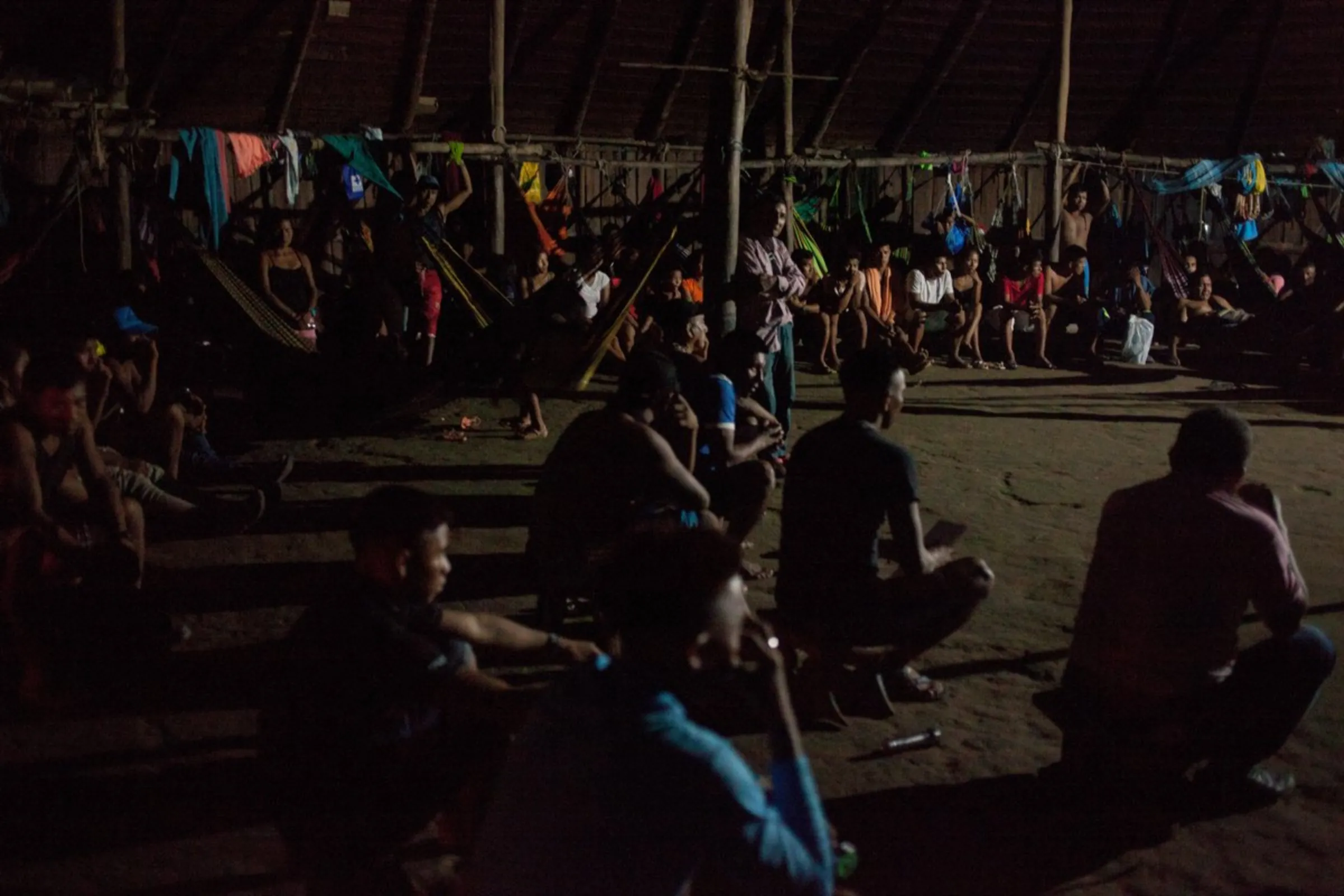 Indigenous people gather in a maloka – a traditional thatched communal dwelling – for an evening meeting in the Puerto Libre community, in Colombia’s southeast Amazonas province, December 19, 2021
