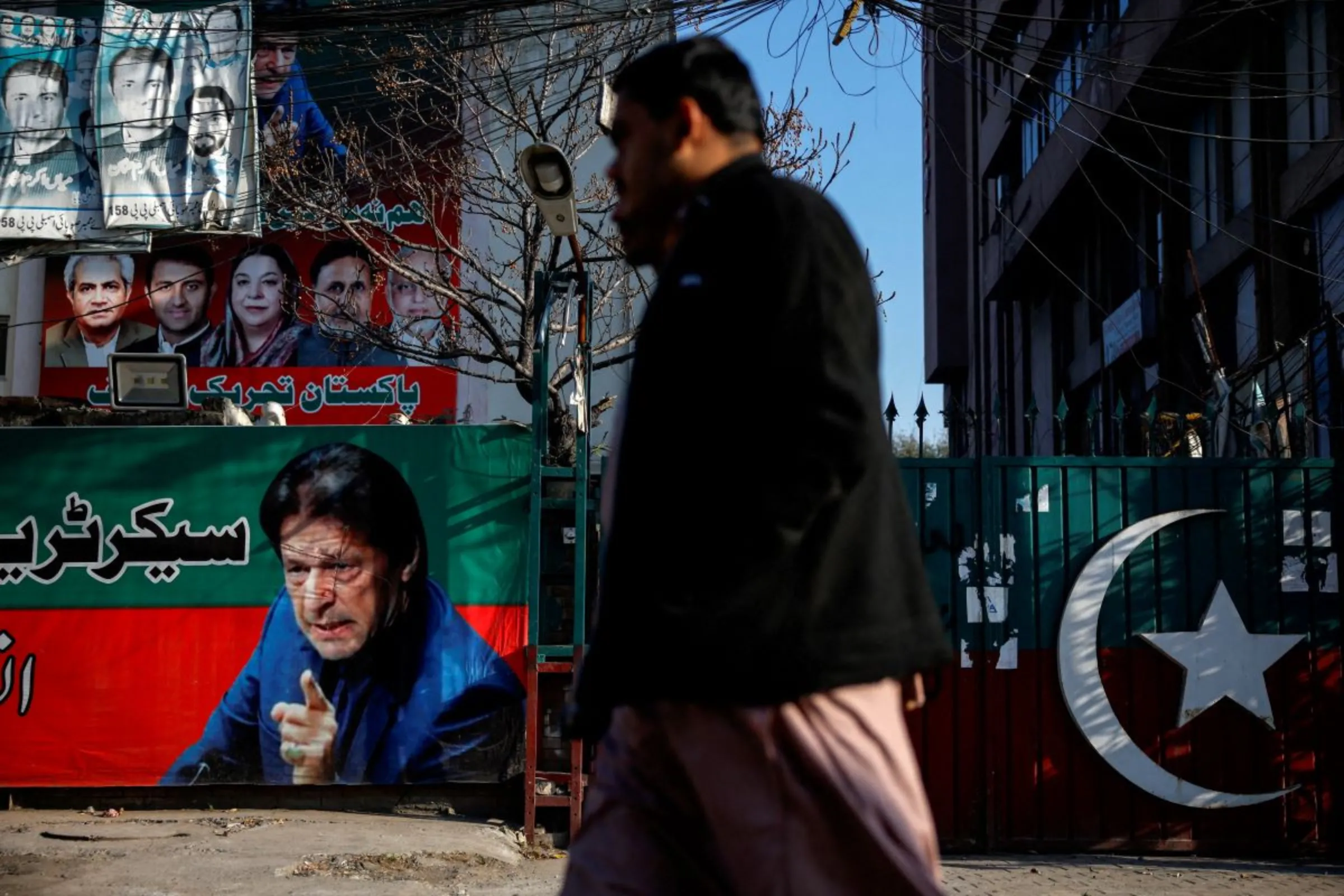 People walk past a banner with a picture of the former Prime Minister Imran Khan outside the party office of Pakistan Tehreek-e-Insaf (PTI), a day after the general election, in Lahore, Pakistan, February 9, 2024. REUTERS/Navesh Chitrakar