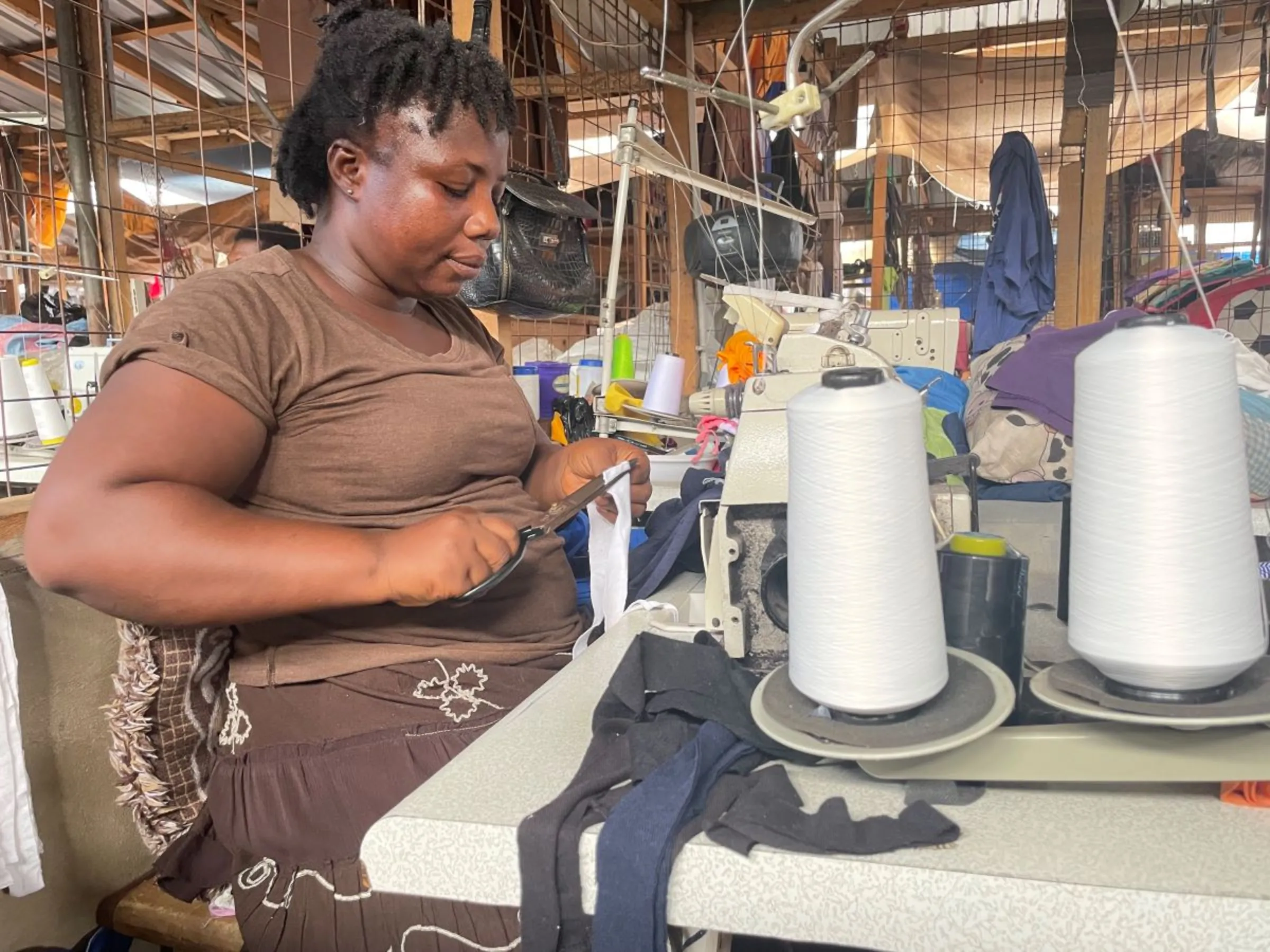 Tailor Lydia Finn upcycles worn T-shirts and used jeans to sew new tops at the market in Accra, Ghana on June 16, 2023. Bukola Adebayo/ Thomson Reuters Foundation