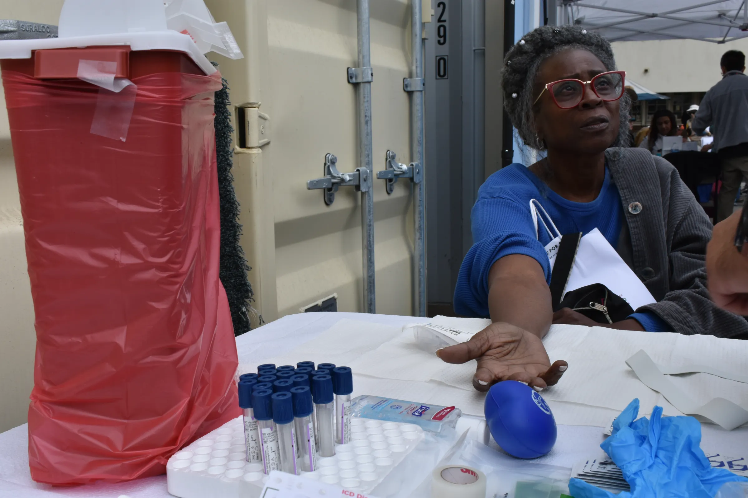 Pasadena resident Patricia Roach listens to information from a Department of Public Health worker before her blood draw, April 27, 2025. Rachel Parsons/Thomson Reuters Foundation