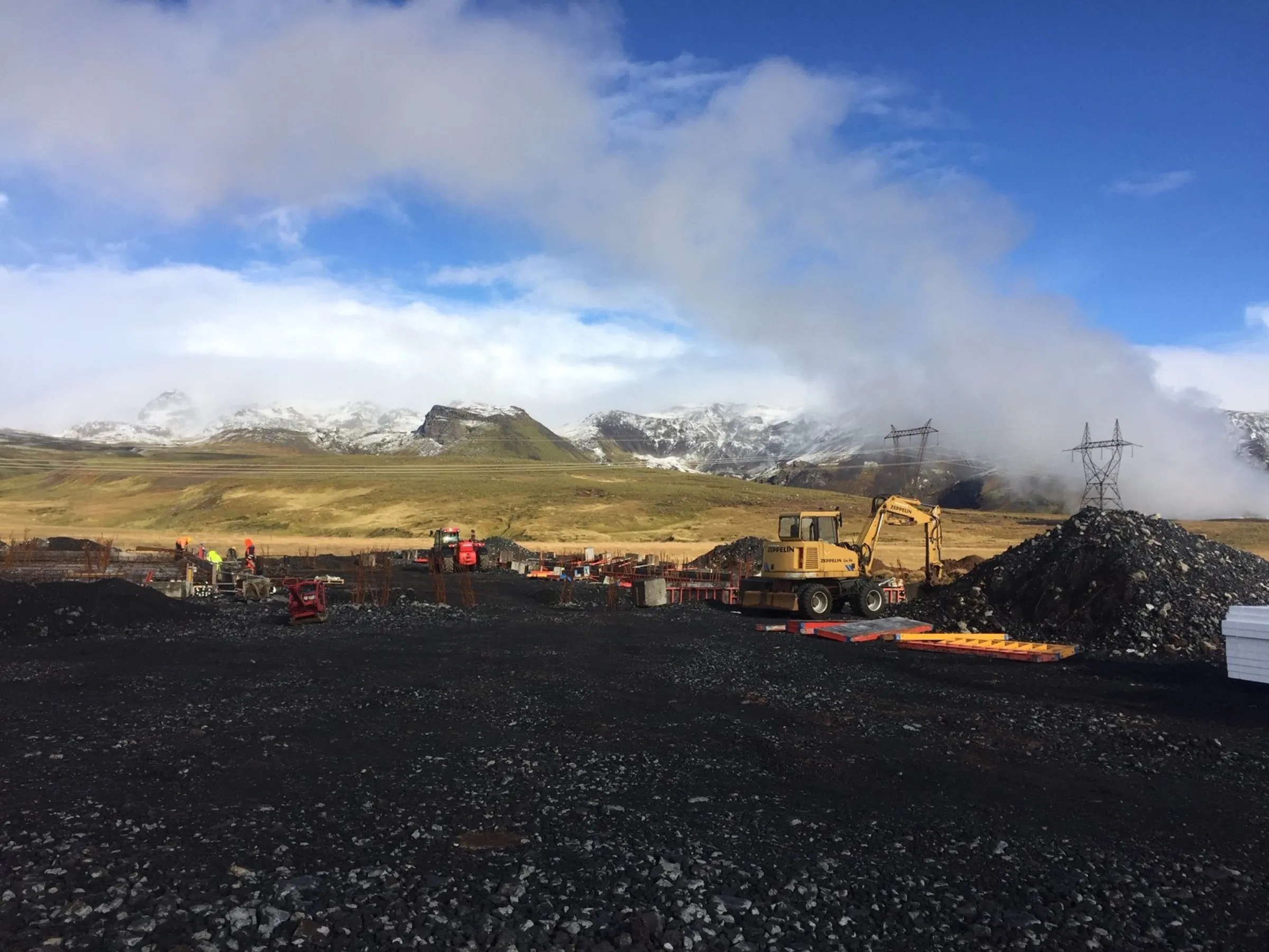 A landscape showing snowy mountaintops with construction work in the foreground