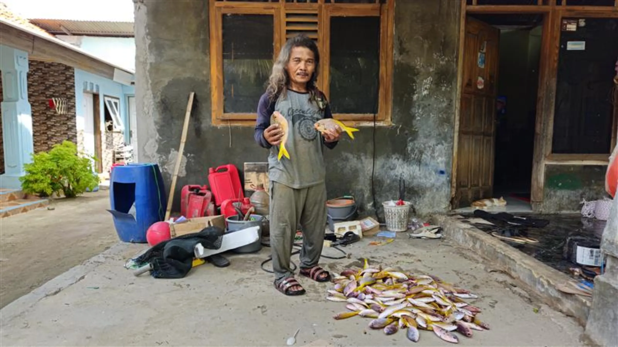 Mustaghfirin, 53, holds yellowtail snappers in front of his home on Pari Island, North Jakarta, Indonesia, October 30, 2025. /Leo Galuh