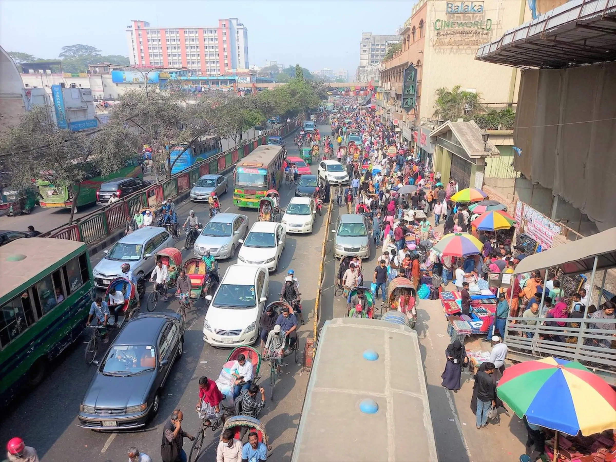 Buses, cars, and rickshaws and people plough through a densely-packed Dhaka street, Dhaka, Bangladesh, February 4, 2023, Thomson Reuters Foundation/Md. Tahmid Zami