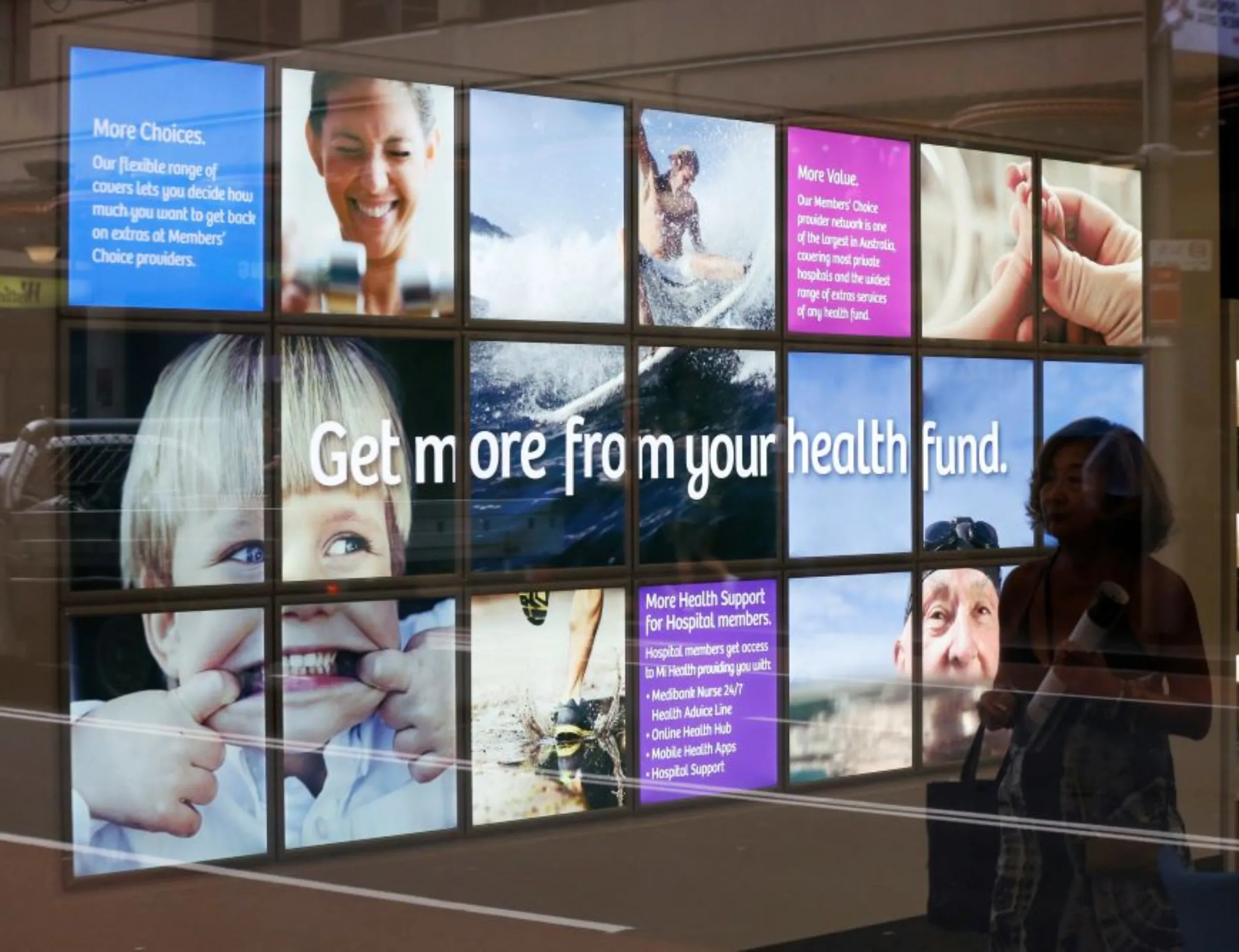 A customer walks in front of an advertising wall inside a Medibank Private shop in Sydney October 27, 2014