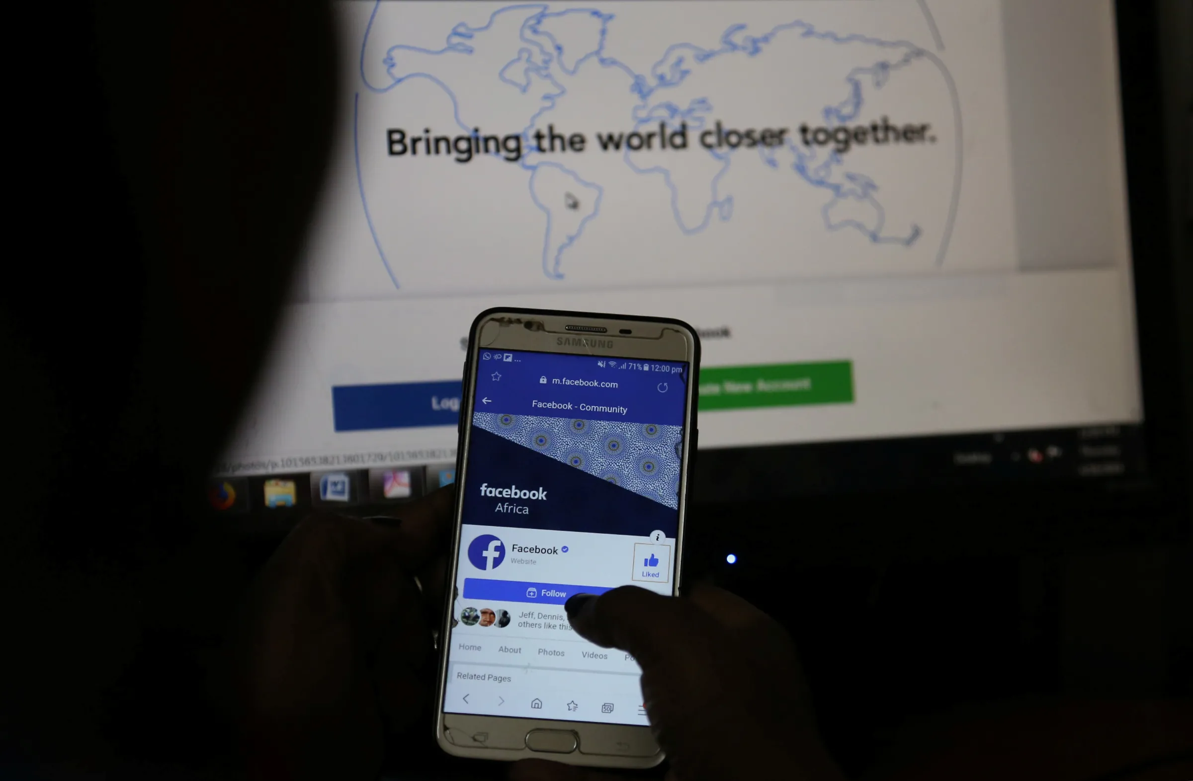 An illustration photo shows the Facebook page displayed on a mobile phone internet browser held in front of a computer screen at a cyber-cafe in downtown Nairobi, Kenya April 18, 2019. REUTERS/Stringer