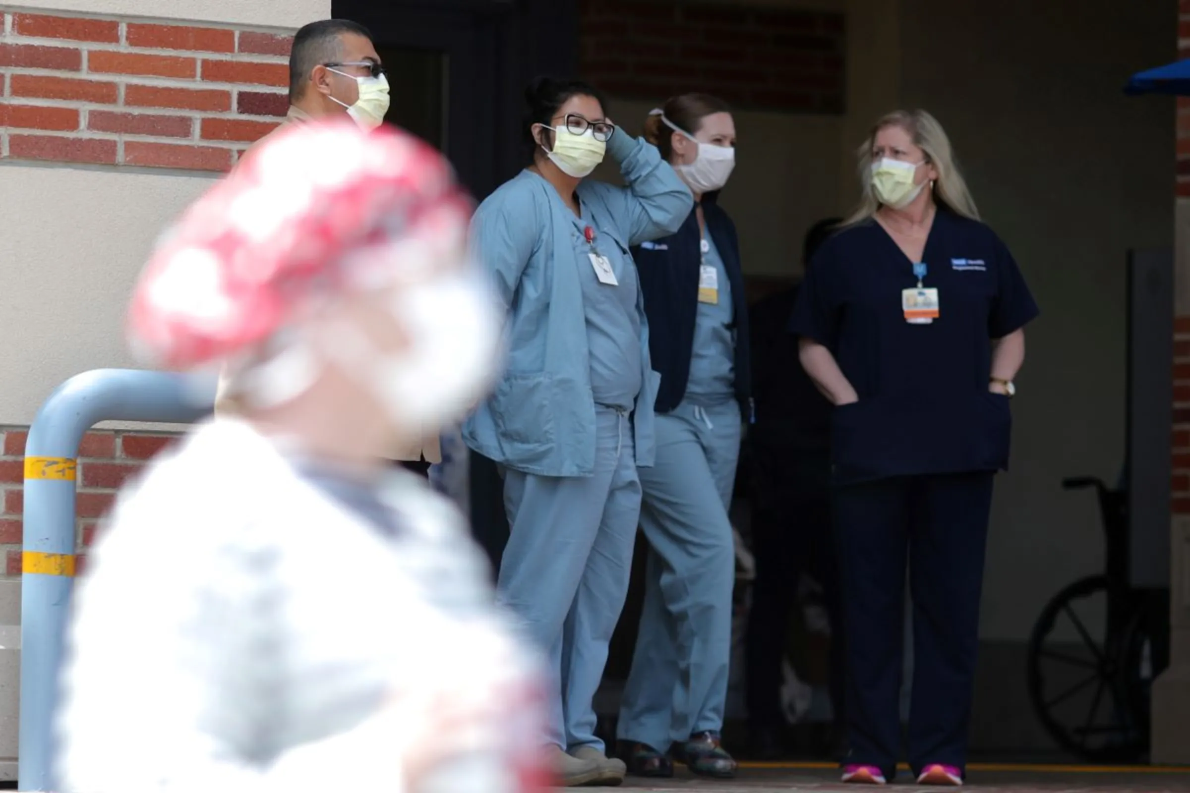 Nurses stand in a hospital doorway watching a nurses’ protest for personal protective equipment at UCLA Medical Center, as the spread of the coronavirus disease (COVID-19) continues, in Los Angeles, California, U.S., April 13, 2020. REUTERS/Lucy Nicholson