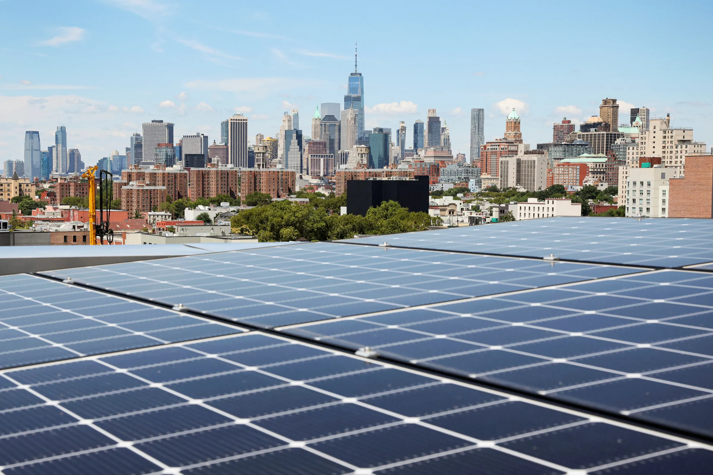 Solar panels are seen along with a view of the neighborhood and lower Manhattan from the rooftop of Timber House, in Brooklyn, New York, U.S., August 16, 2022. REUTERS/Brendan McDermid