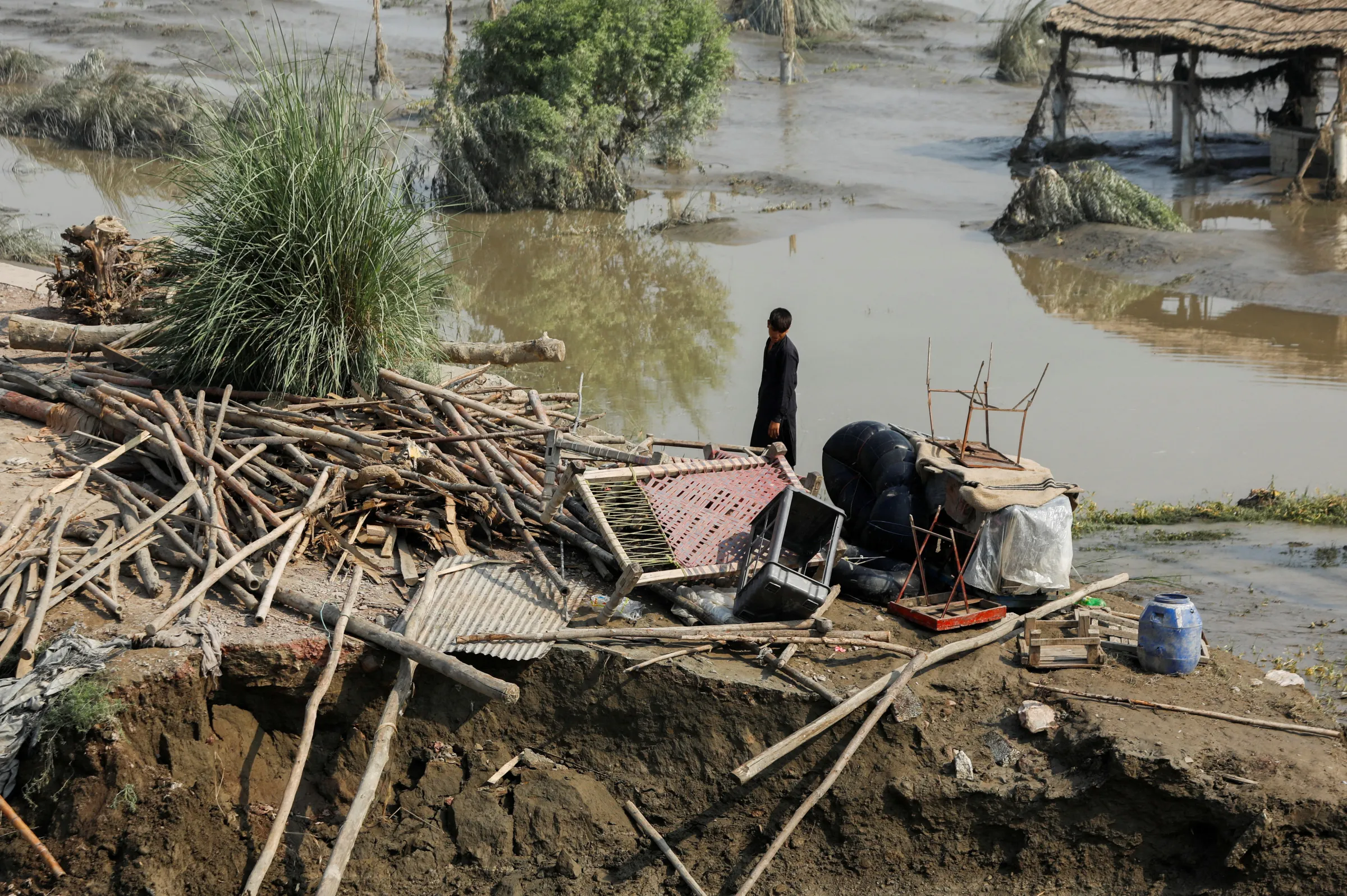A flood victim stands in his damaged house, following rains and floods during the monsoon season, in Nowshera, Pakistan