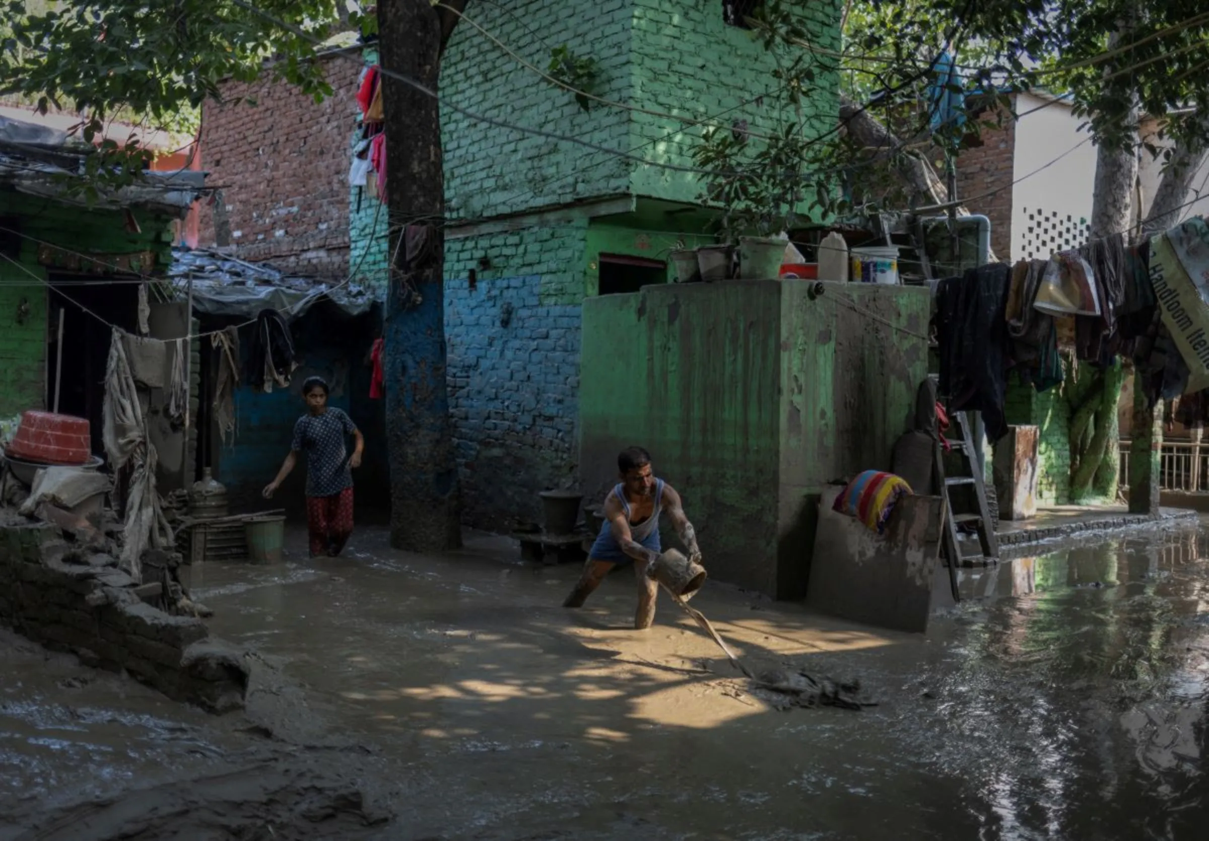 A man cleans the mud outside his house after flood water recedes from a residential area that was flooded by the overflowing of the river Yamuna following heavy rains, in New Delhi, India, July 17, 2023. REUTERS/Adnan Abidi