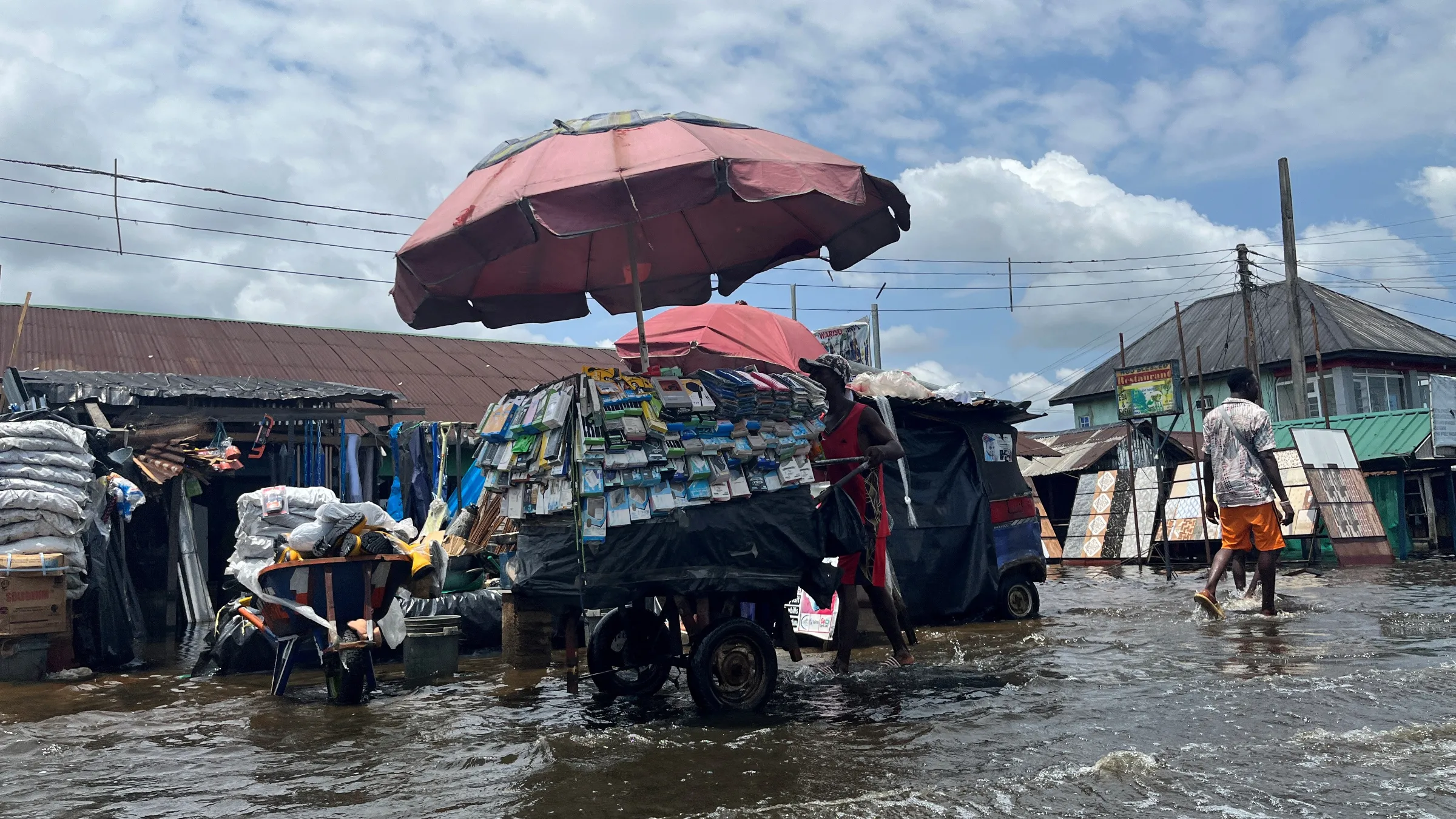 A man pushes a cart across the street as flood water continues to displace people in Yenagoa Nigeria, October 18, 2022