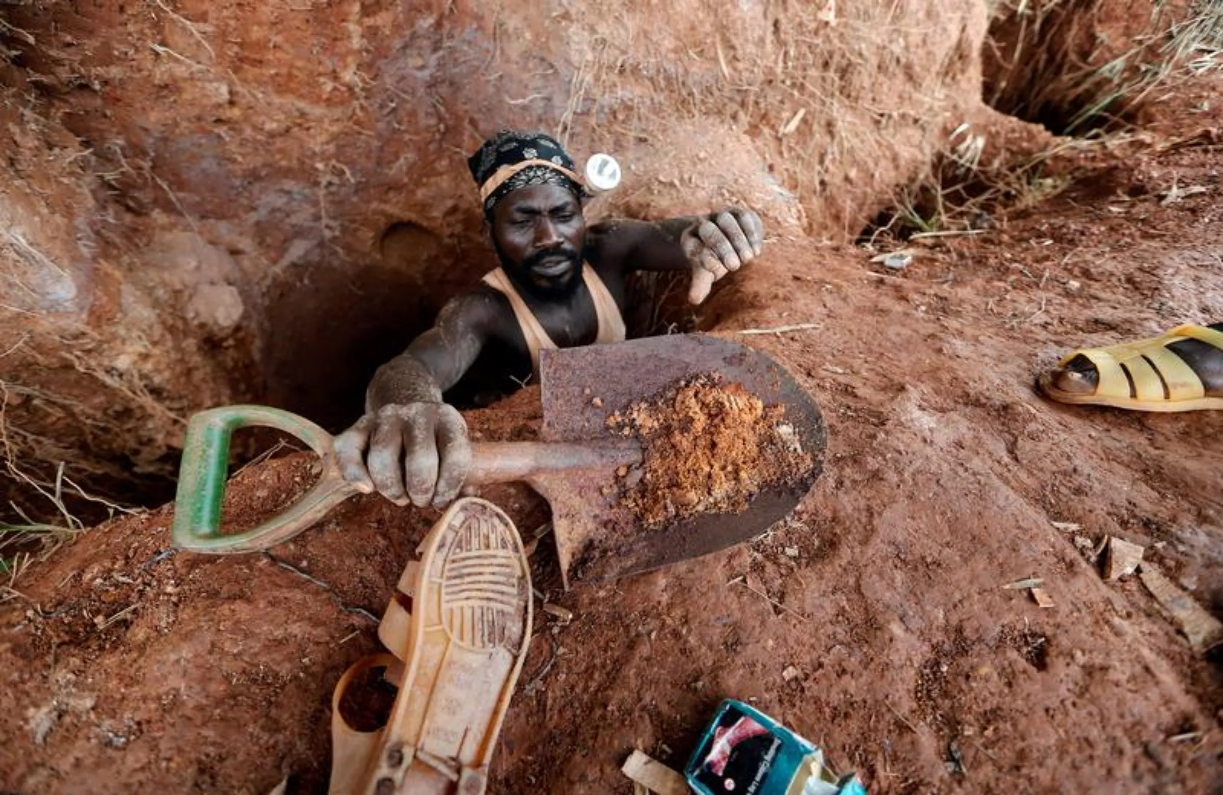 An informal gold miner carries a shovel as he climbs out from inside a pit at the site of Nsuaem-Top, Ghana, November 24, 2018. REUTERS/Zohra Bensemra