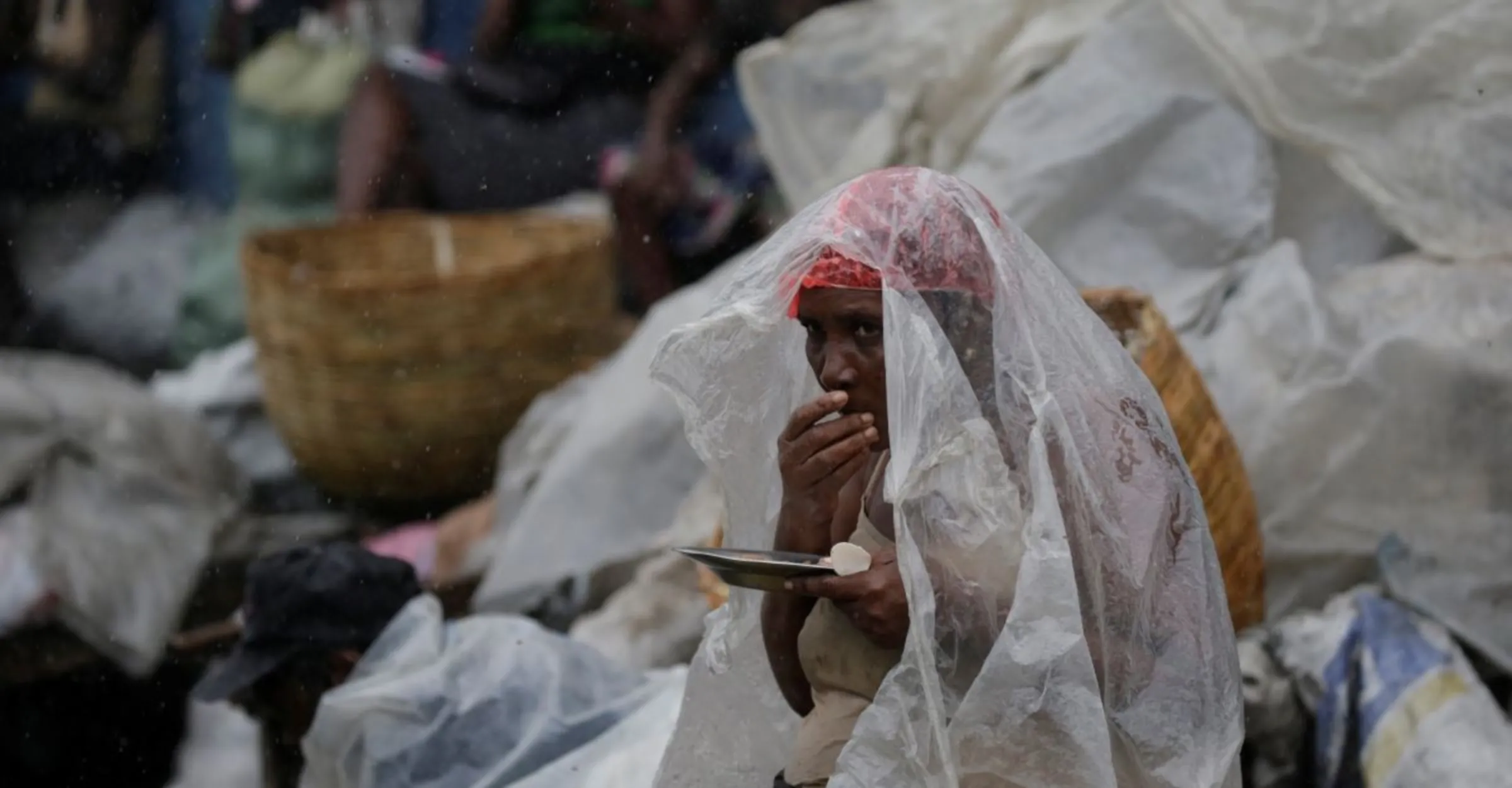 A woman protects herself from rain brought by Hurricane Irma as she eats lunch in a street of Cap-Haitien, Haiti, September 7, 2017. REUTERS/Andres Martinez Casares