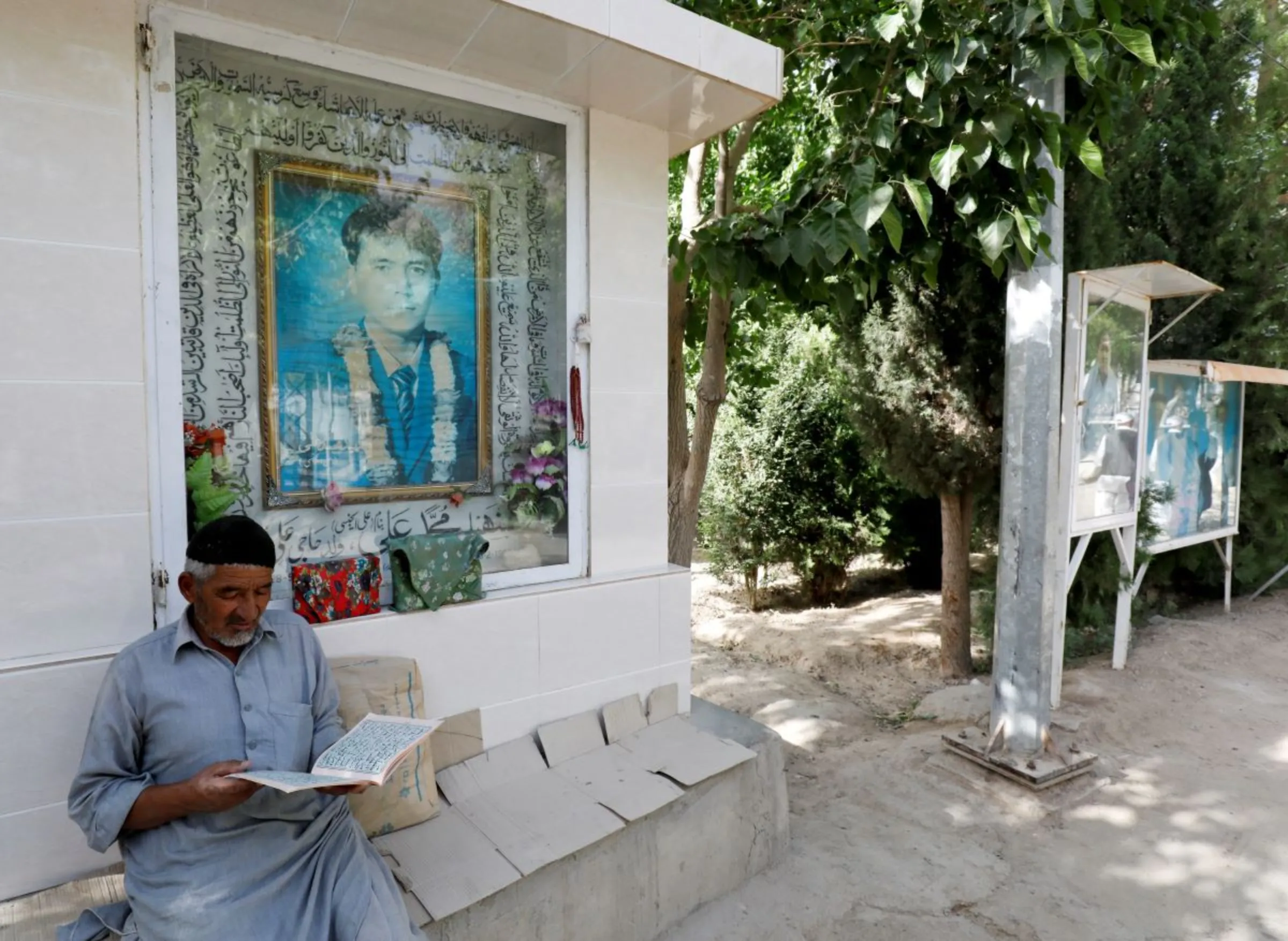 A Hazara man reads the Koran along a passageway with photos of deceased victims who lost their lives during target killings and bomb attacks, at the graveyard called Shuhda Qabristan (martyred graveyard) in Mariabad, Quetta, Pakistan, June 13, 2019. REUTERS/Akhtar Soomro