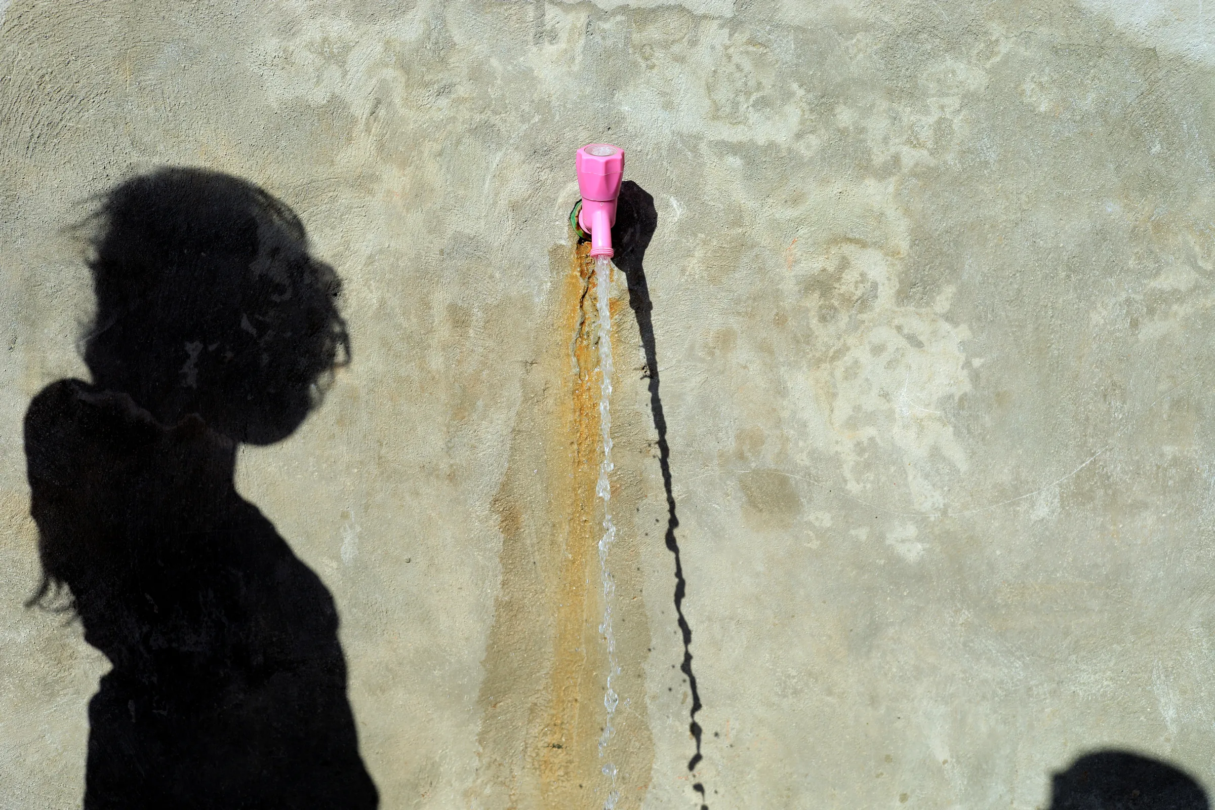 The shadow of an internally displaced girl who fled Raqqa is cast at the water point at a camp in Ain Issa, north of Raqqa