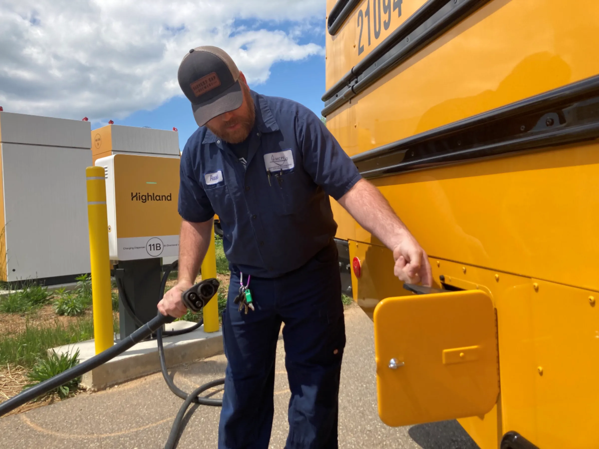 Michael C. Austin, lead technician with the Montgomery County Public Schools Department of Transportation, plugs in an electric school bus in Rockville, Maryland, in April 2023. Thomson Reuters Foundation/Carey L. Biron