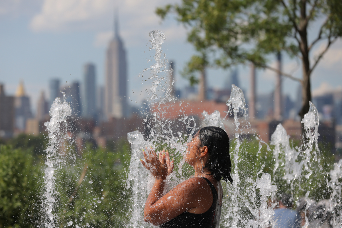 A person cools off in a water feature in Domino Park as a heat wave hit the region in Brooklyn, New York City, U.S.