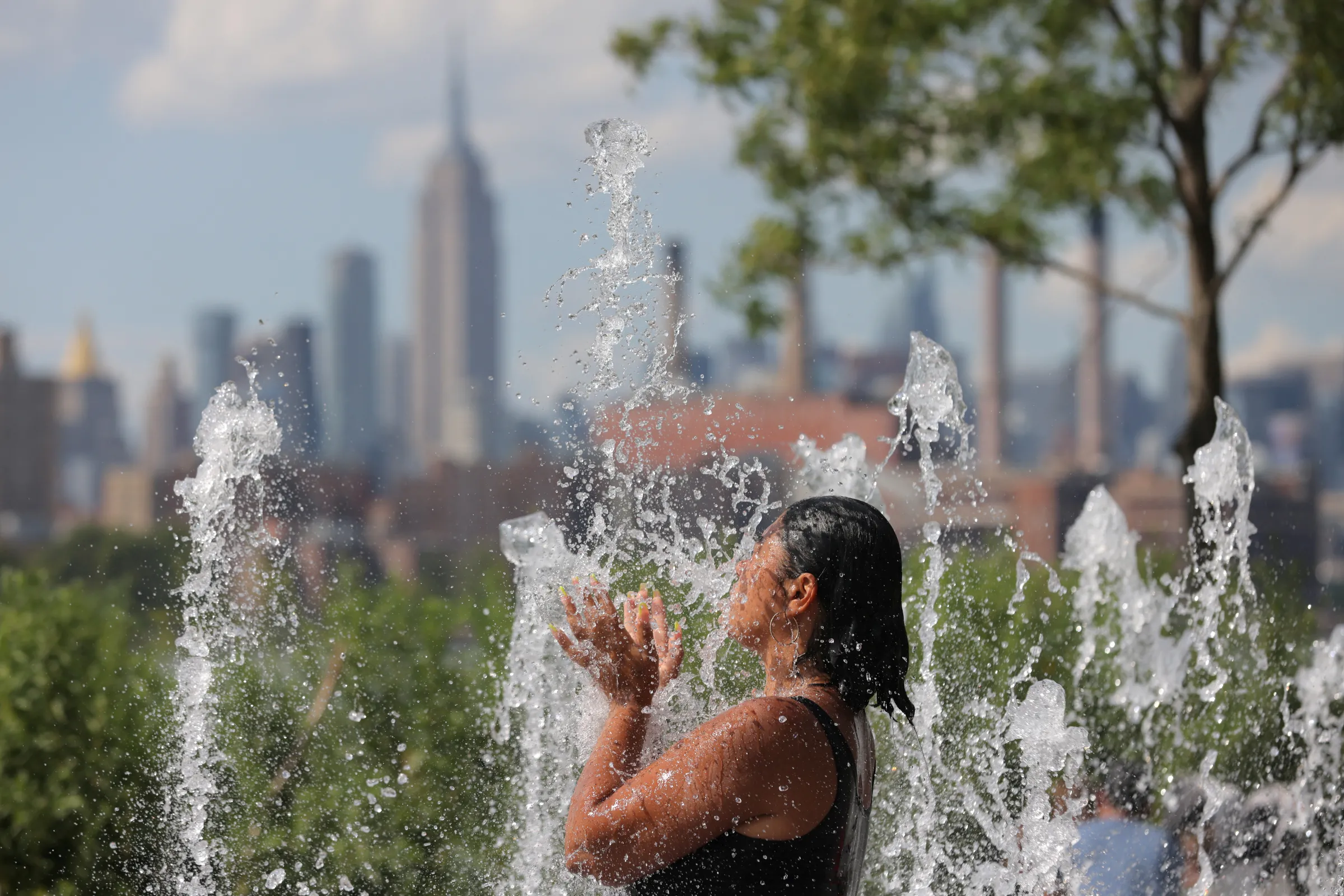 A person cools off in a water feature in Domino Park as a heat wave hit the region in Brooklyn, New York City, U.S.