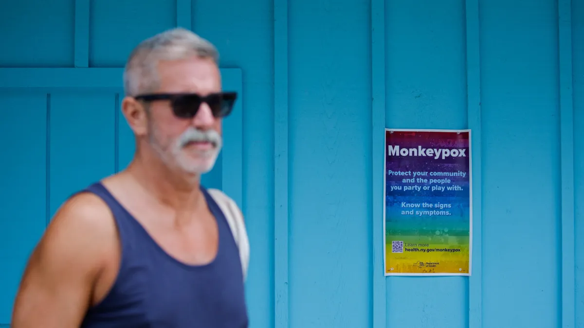 A man walks near a poster with monkeypox information at a local store
