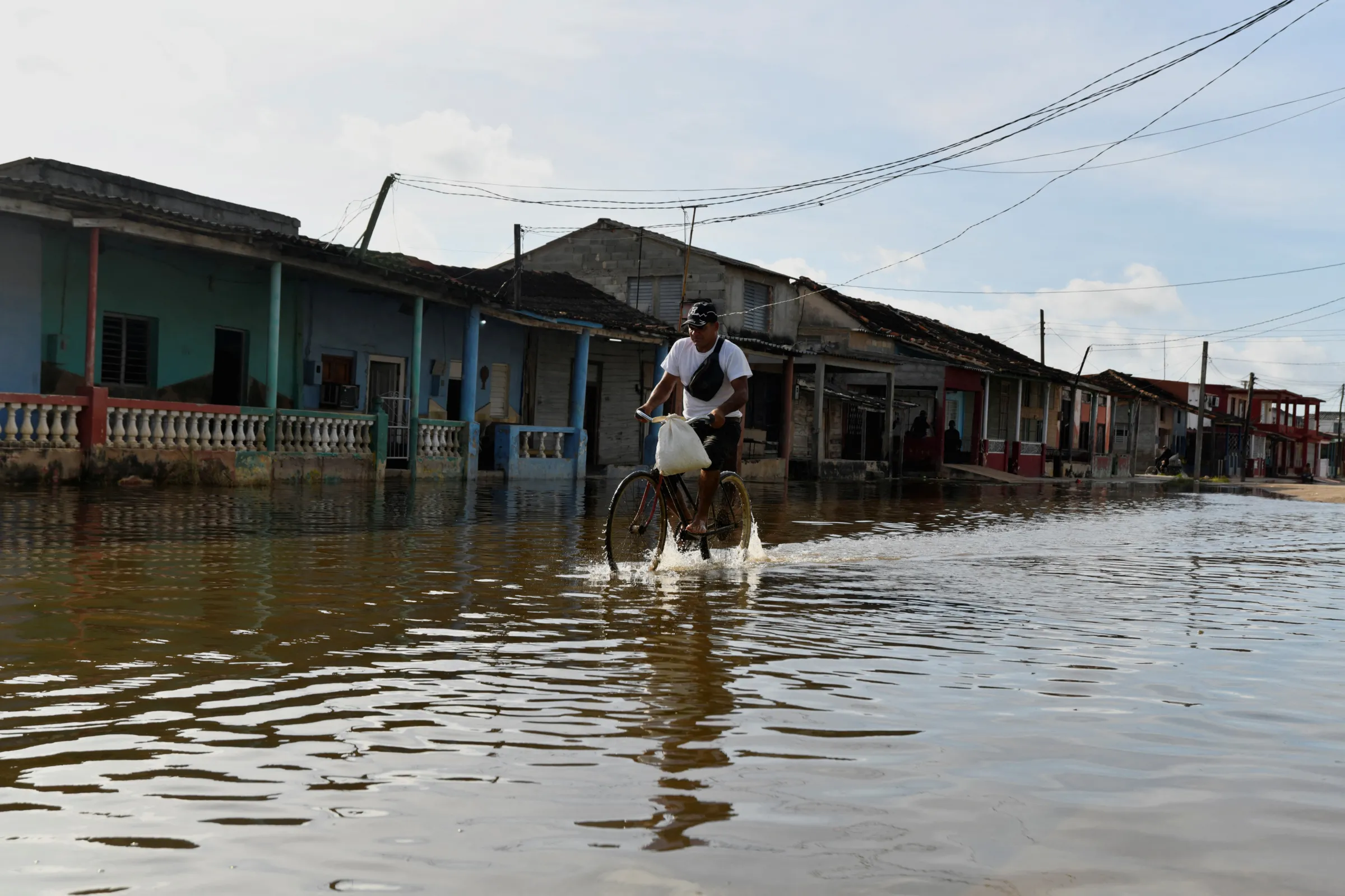 A man cycles through a flooded street as Hurricane Milton approaches the Cuban coast in Batabano, Cuba, October 8, 2024. REUTERS/Norlys Perez