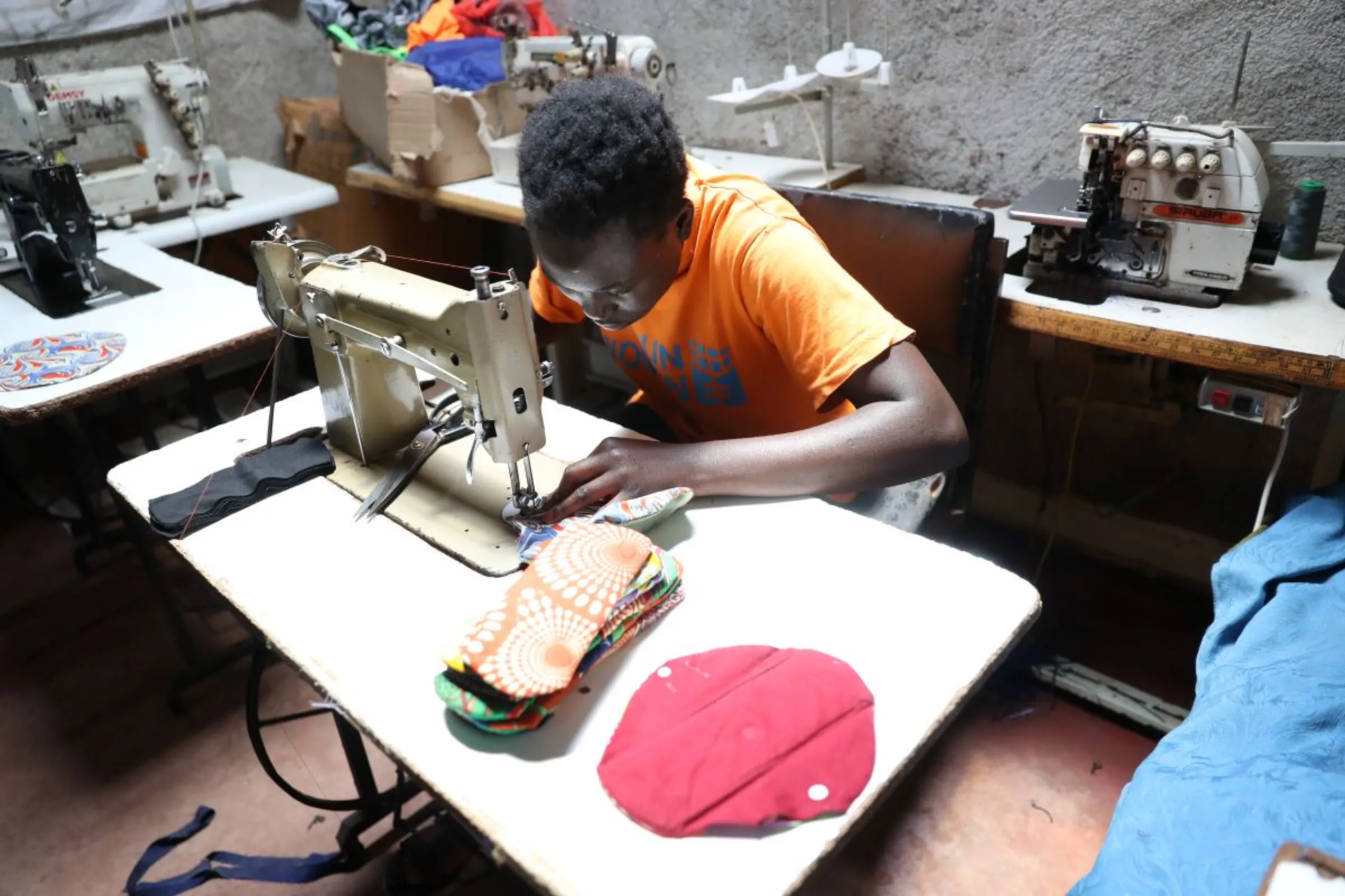 A woman stitches a reuseable cloth sanitary pad at charity Amani Kibera in Kibera informal settlement in Nairobi, Kenya on April 15, 2023