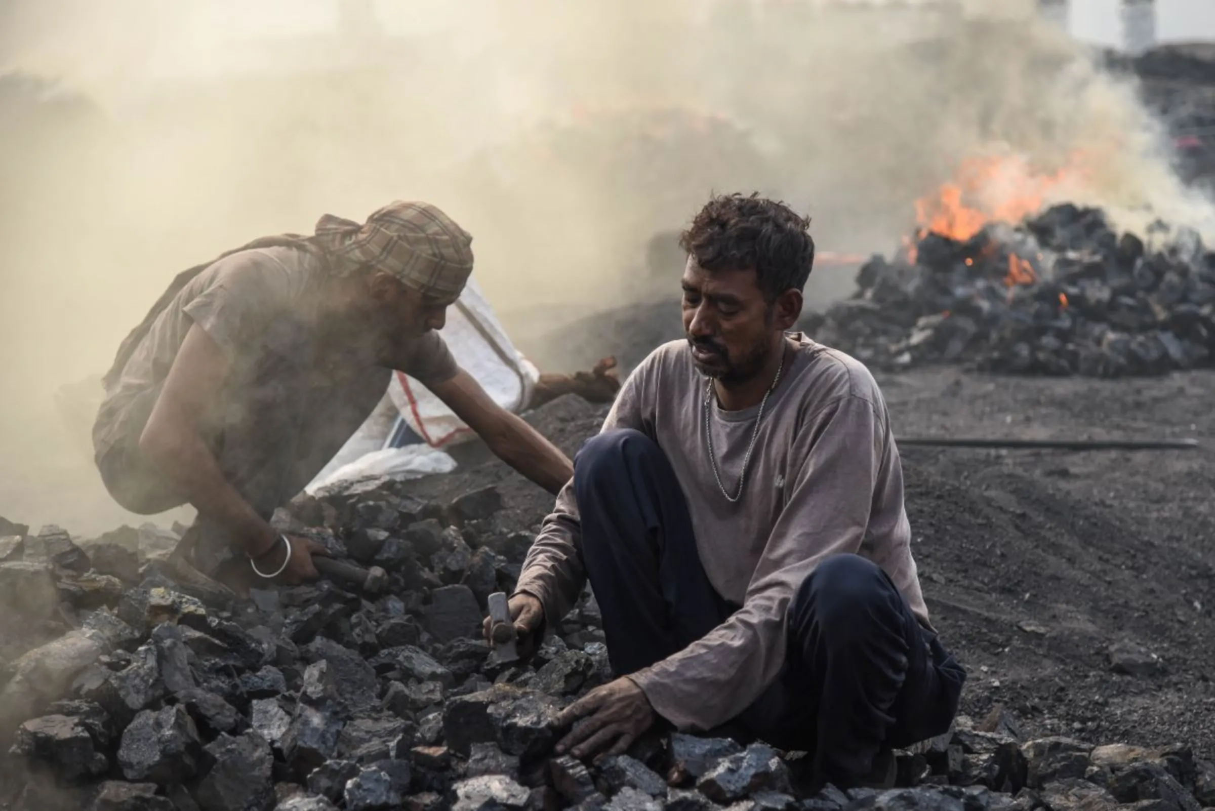 Sanjay Kumar Pandit breaks large rocks of coal into smaller pieces at a burning coalfield in Jharia, India, November 11, 2022. Thomson Reuters Foundation/Tanmoy Bhaduri