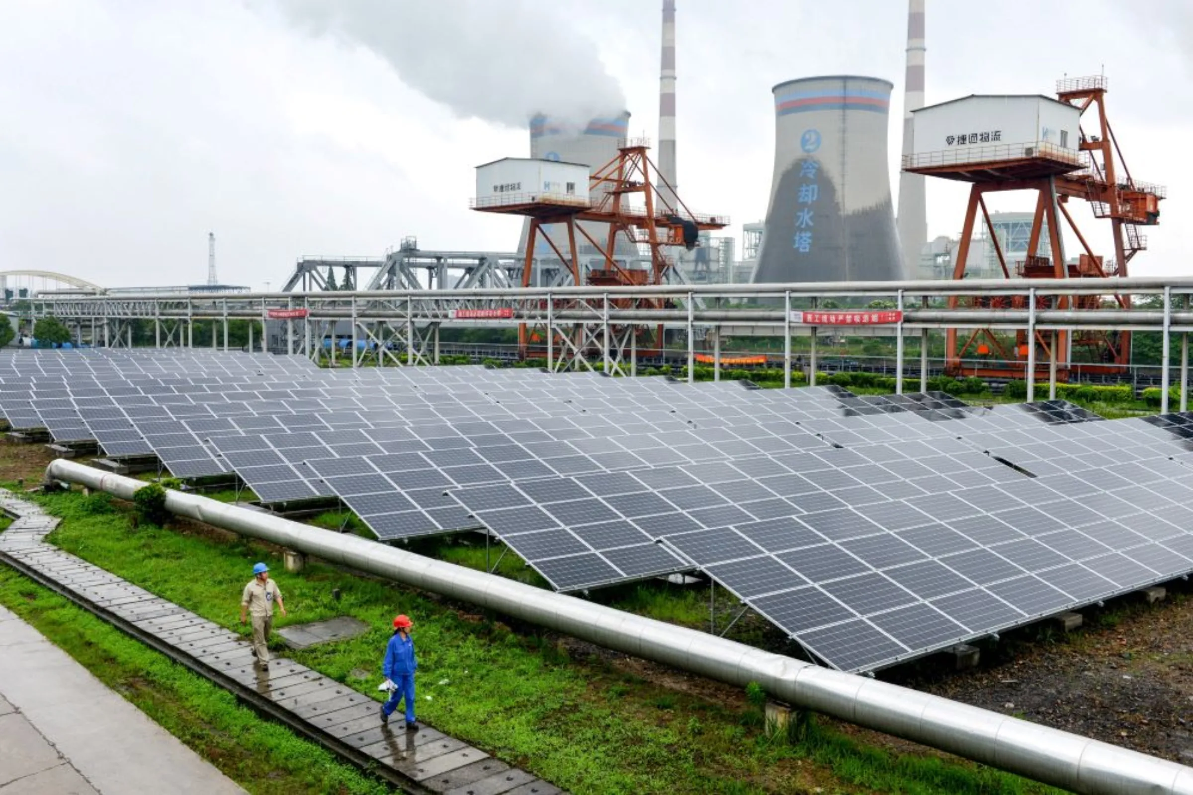 Employees check solar panels, as they work on a grid-connected photovoltaic power generation project, at a power plant in Changxing County, Zhejiang Province, China June 13, 2017