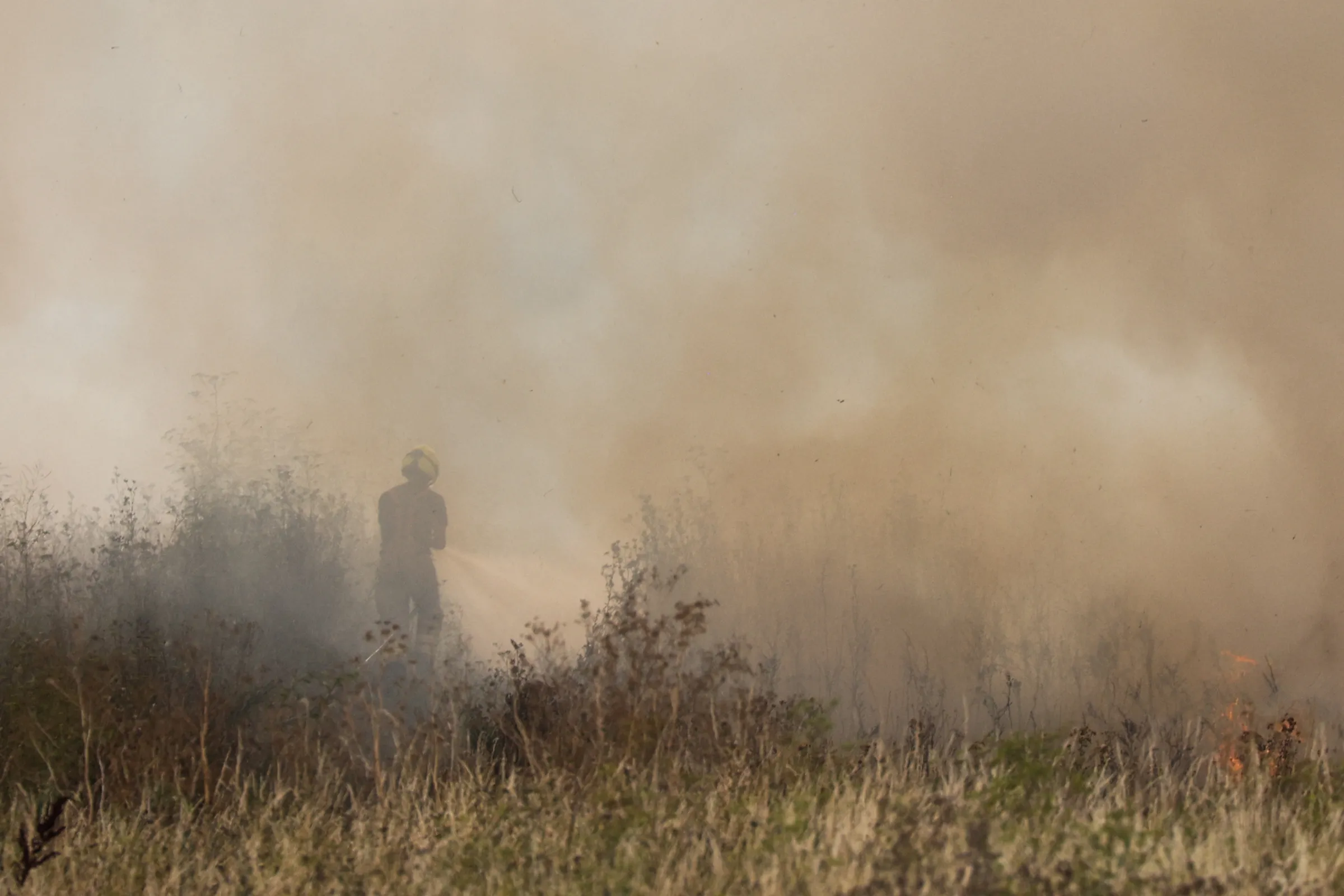 A firefighter works to contain a grass fire during a heatwave in Snodland, near Maidstone, Britain, August 14, 2022. REUTERS/Kevin Coombs