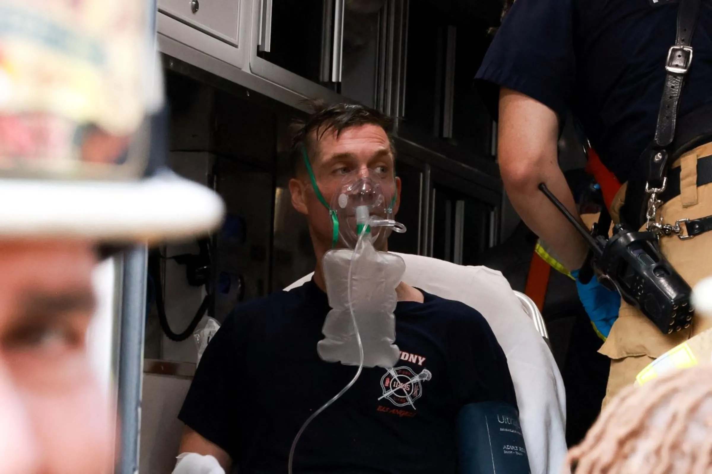 An injured firefighter receives medical attention after a construction crane caught fire on a high-rise building in Manhattan, New York City, U.S., July 26, 2023