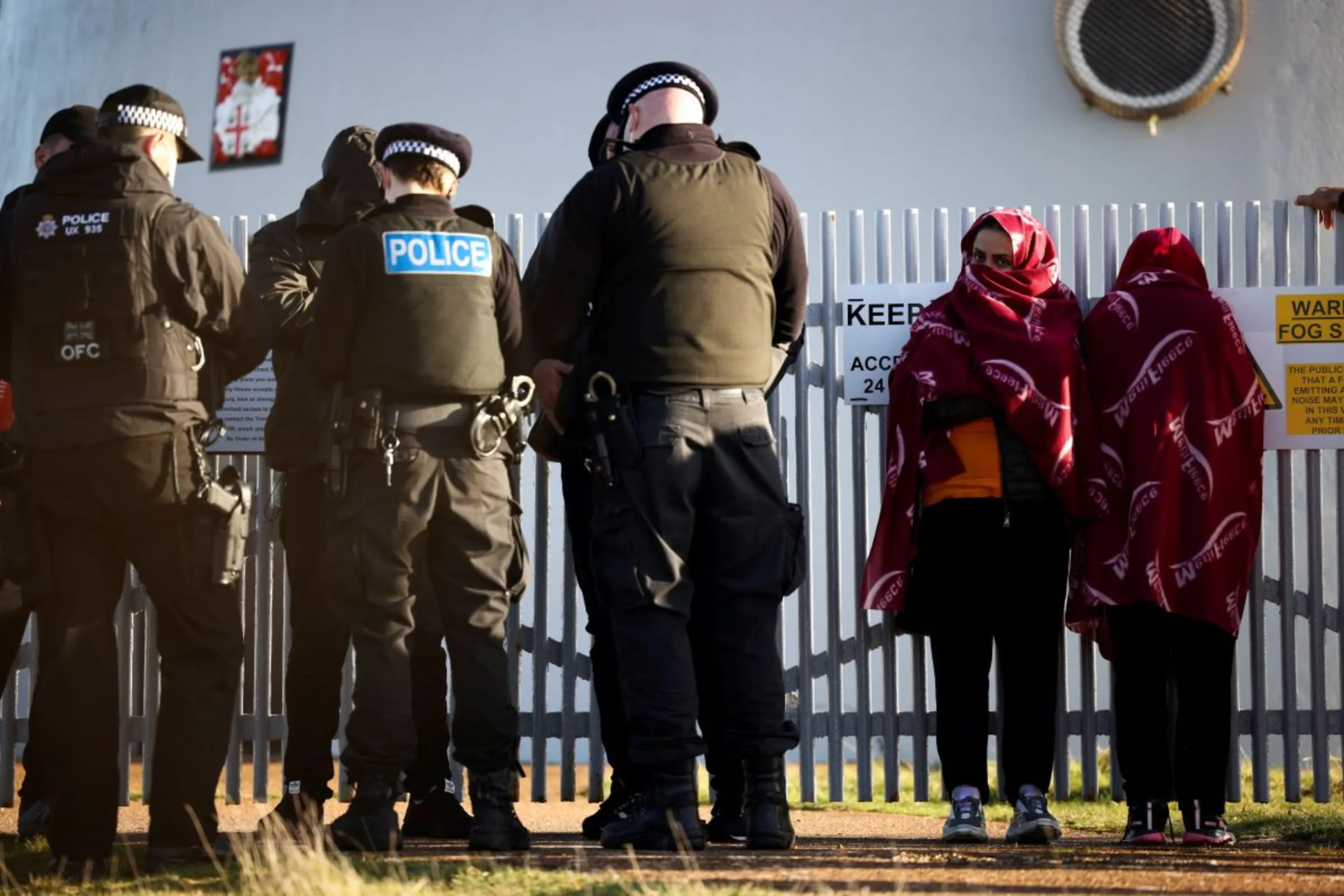Migrants stand with police on the beach after crossing the English Channel in an inflatable dinghy, in Dungeness, Britain, January 18, 2022. REUTERS/Henry Nicholls