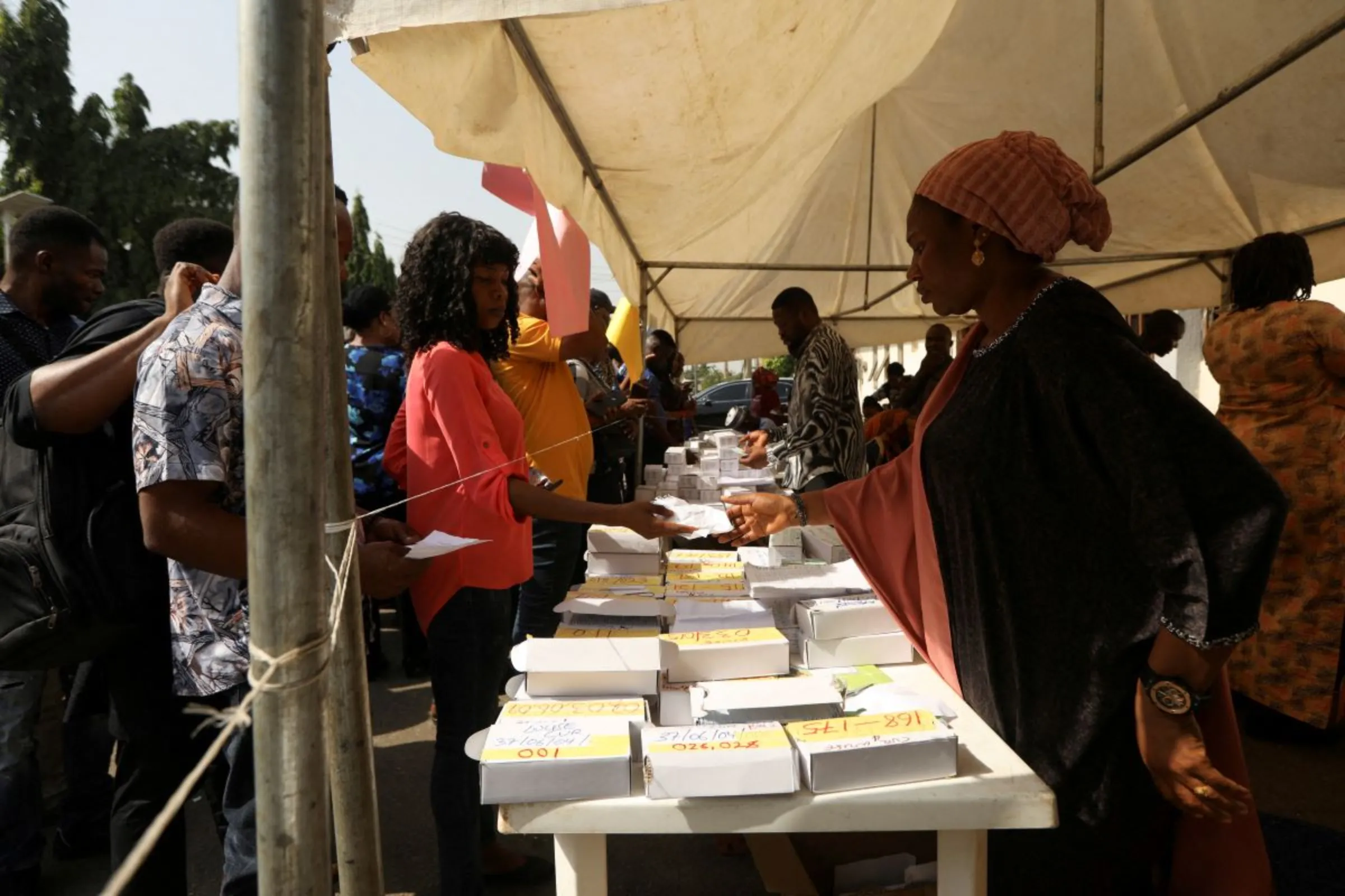 A woman presents a paper to an INEC worker during the collection of a permanent voters card at the INEC office in area 10, in Abuja, Nigeria December 13, 2022. REUTERS/Afolabi Sotunde