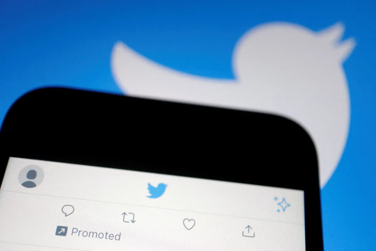 A promoted tweet on Twitter app is displayed on a mobile phone near a Twitter logo, in this illustration picture taken Sept. 8, 2022. REUTERS/Florence Lo