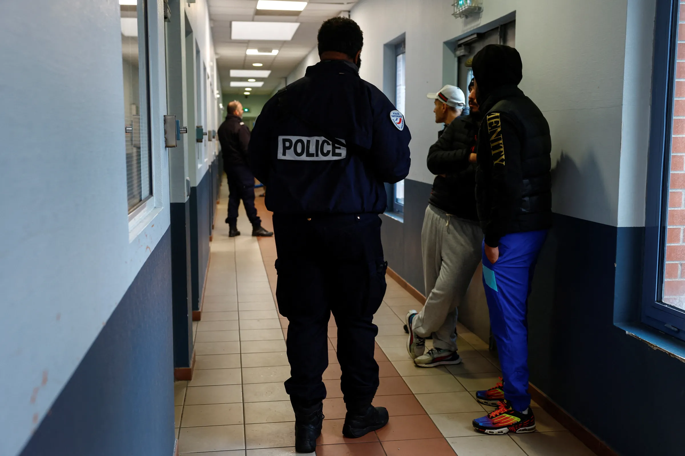 Migrants stand behind barriers in the courtyard of a detention centre, where migrants are sent to await deportation, in Mesnil-Amelot near Paris, France, November 18, 2024. REUTERS/Stephanie Lecocq