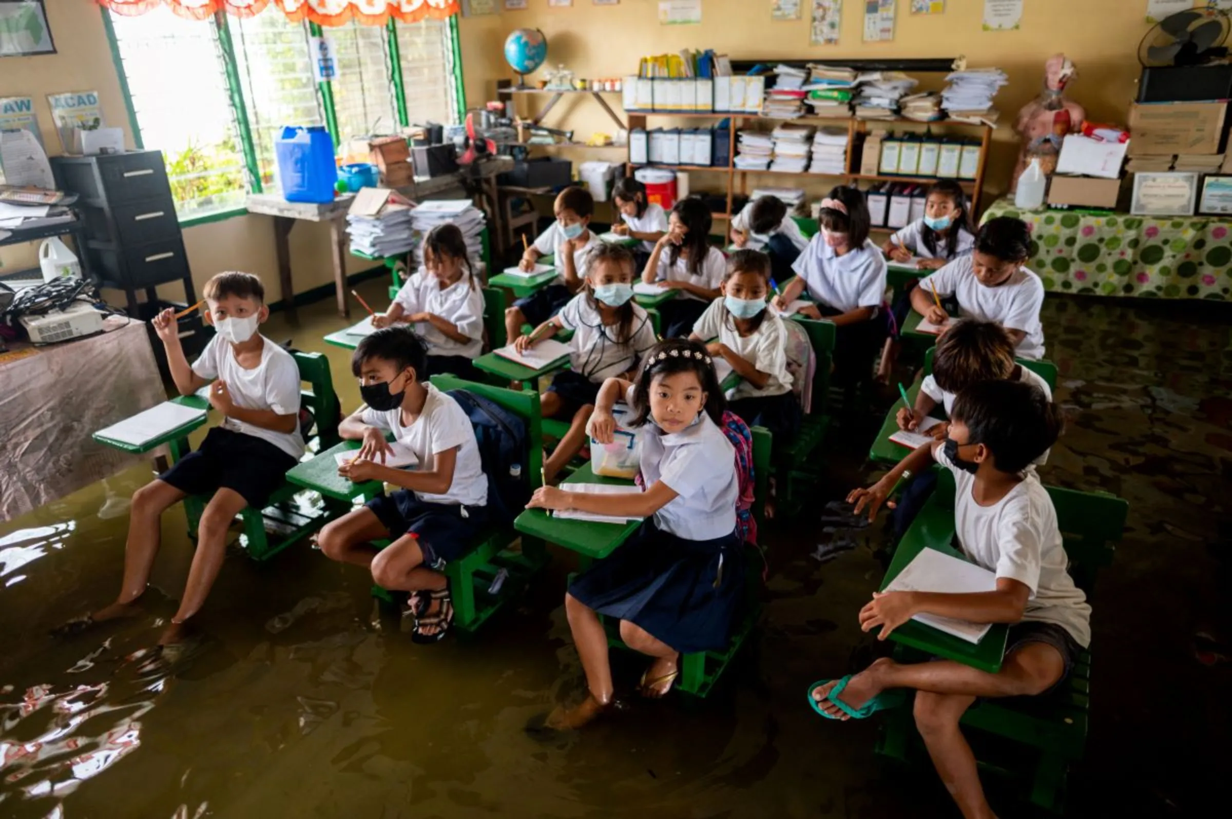 Students attend the first day of in-person classes, at a flooded school due to high tide, in Macabebe, Pampanga province, Philippines, August 22, 2022. REUTERS/Lisa Marie David