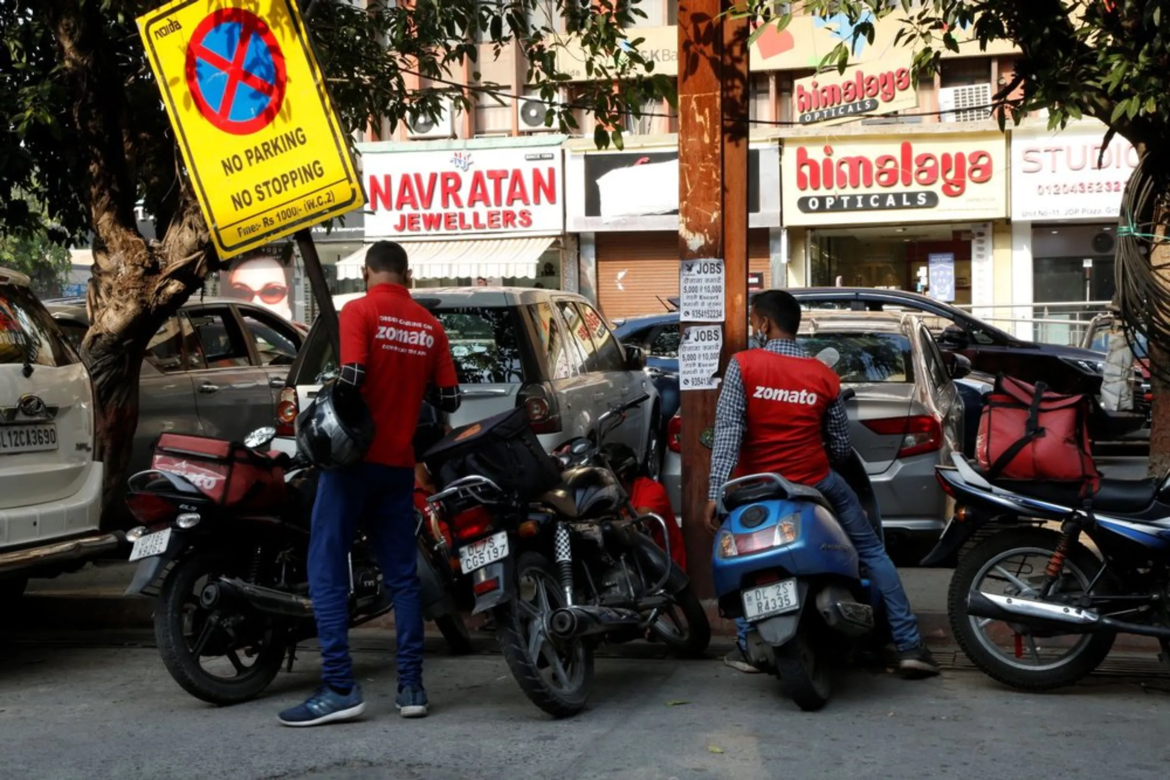 Food couriers wait outside restaurants with their scooters to pick up orders in Noida, India on October 7, 2021