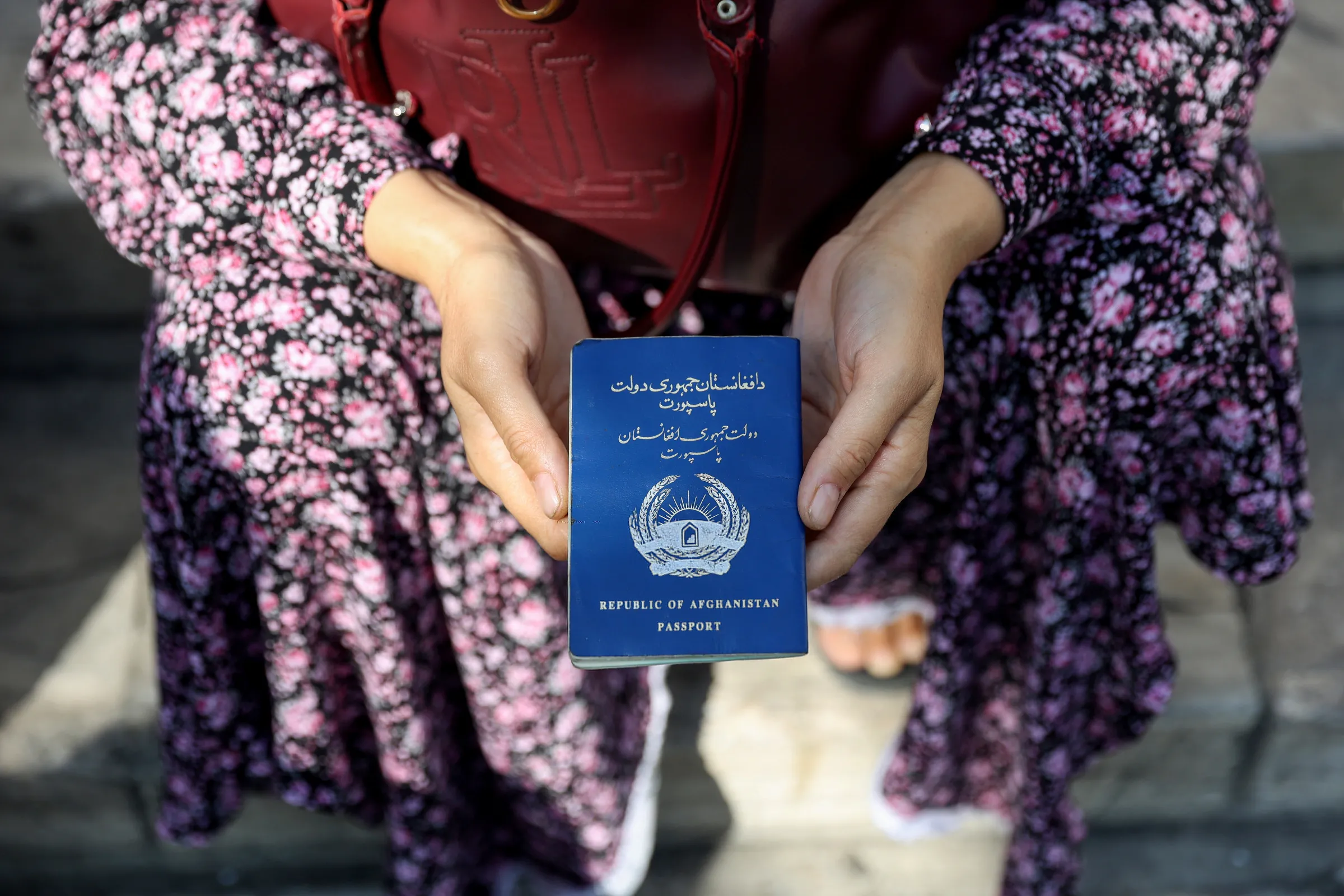 An Afghan refugee holds her passport in front of the German Embassy ​in a bid to acquire refugee visas from the European country, in Tehran, Iran September 1, 2021.