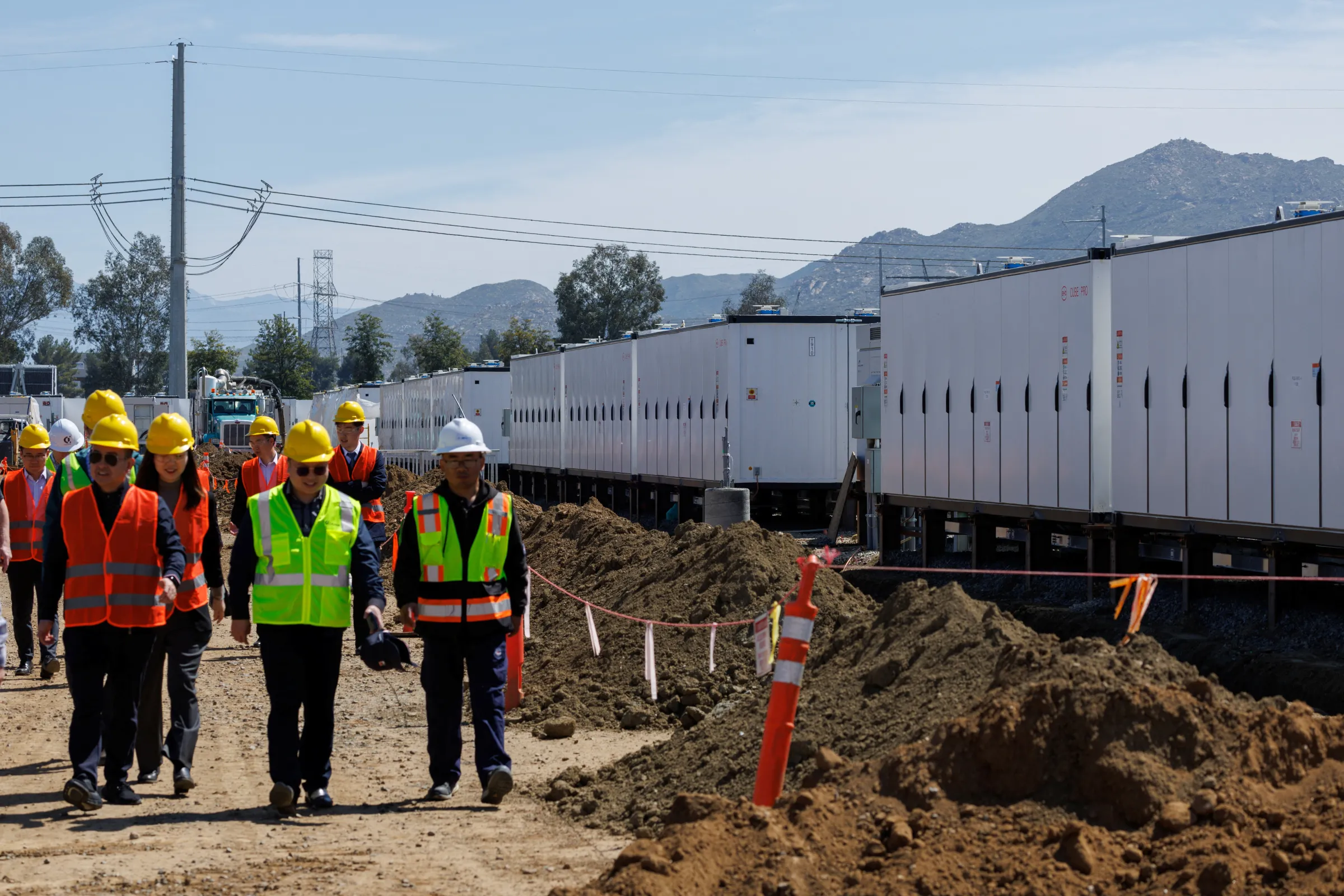 Officials walk past rows of Chinese batteries while they tour California's largest battery storage facility, as it nears completion in California, U.S., March 28, 2024. REUTERS/Mike Blake
