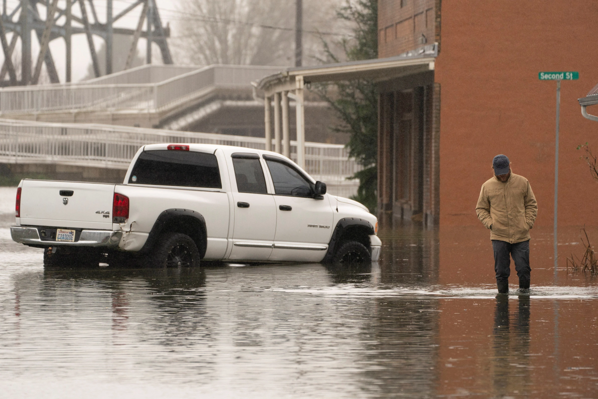 A person walks through floodwater, as an atmospheric river brings rain and flooding to the Pacific Northwest, in Sultan, Washington, U.S., December 10, 2025. REUTERS/David Ryder