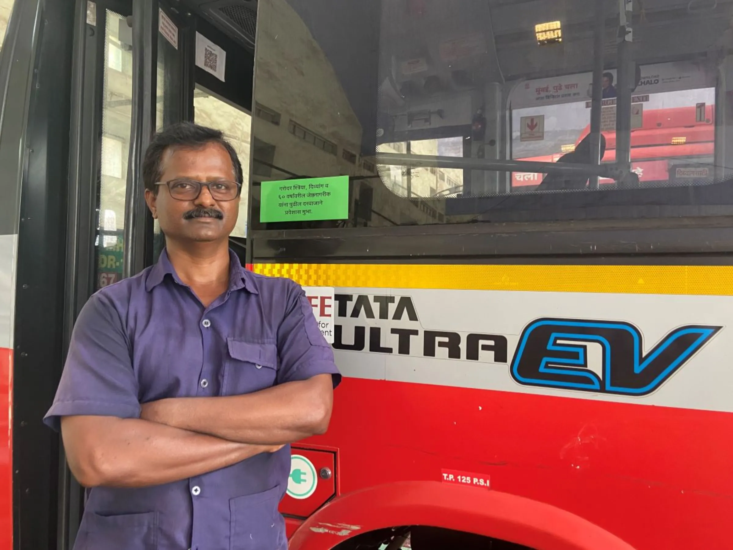 Sanjay Shashikant Kerkar, senior mechanic with Mumbai's public transport body, poses for a picture in front of an electric bus in Mumbai, India, April 19 2023. Thomson Reuters Foundation/Roli Srivastava
