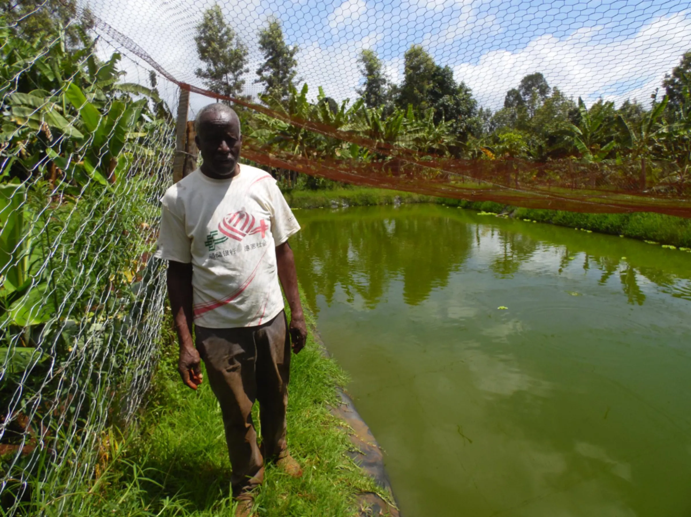 Elijah Murithi poses for a photo next to his fish pond in Kibingo, central Kenya, 7 December 2022