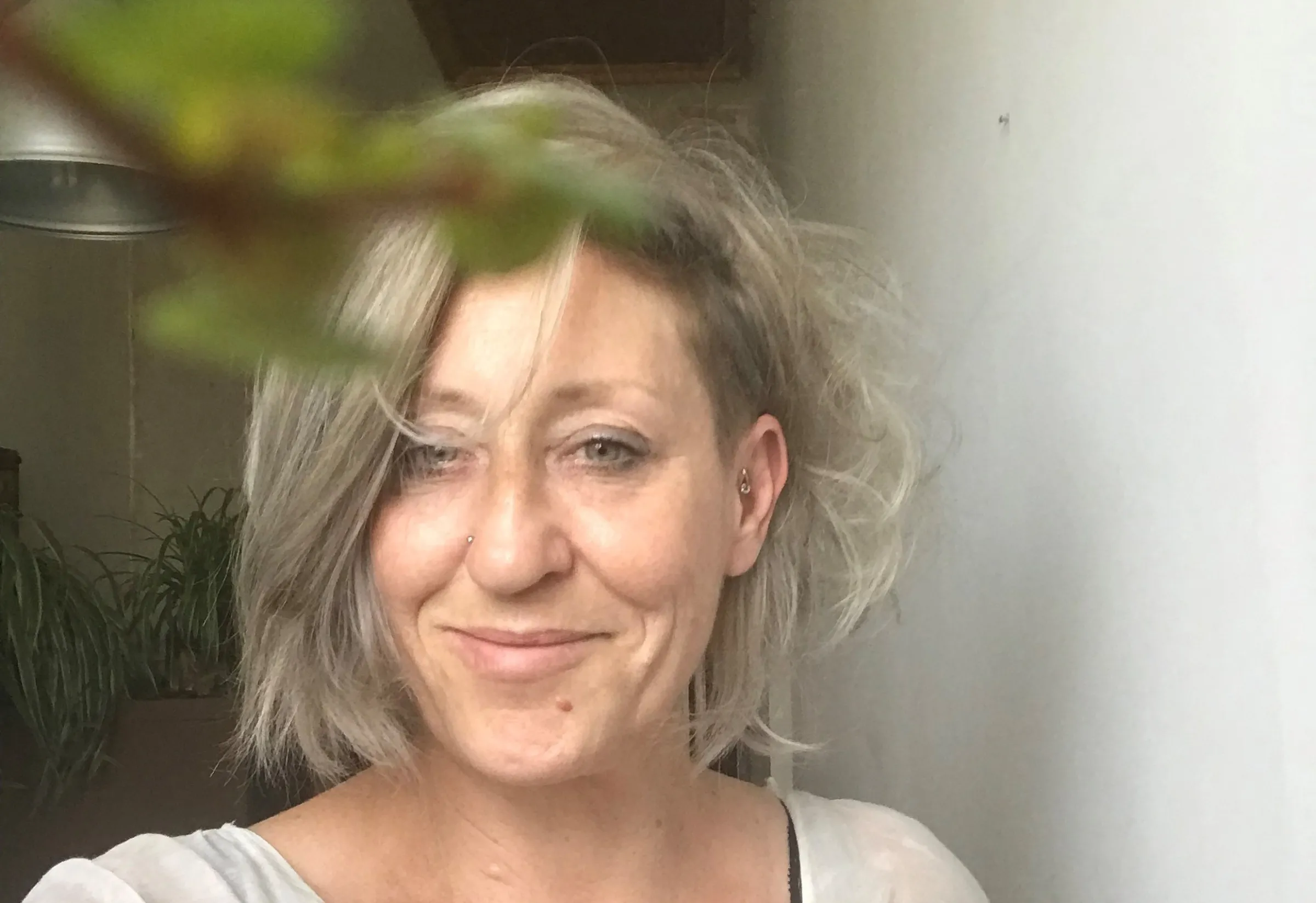 A woman poses for a selfie in front of a white wall