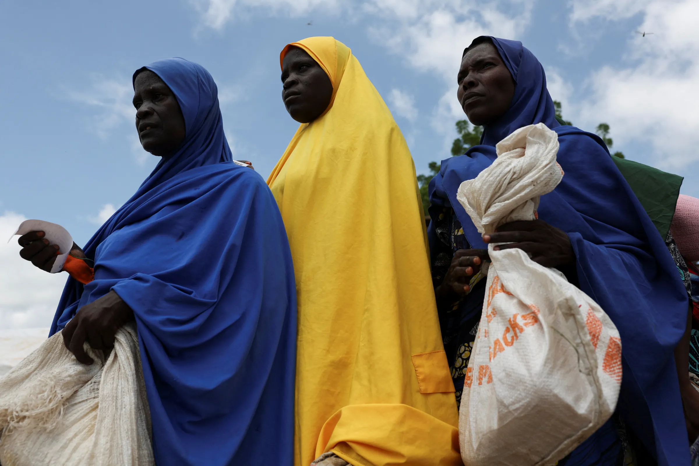 Beneficiaries from different Internally Displaced Persons camps hold food sacks while waiting in line to receive support following the exit of USAID, at a World Food Programme distribution centre in Dikwa, Borno State, Nigeria, August 27, 2025. REUTERS/Sodiq Adelakun.