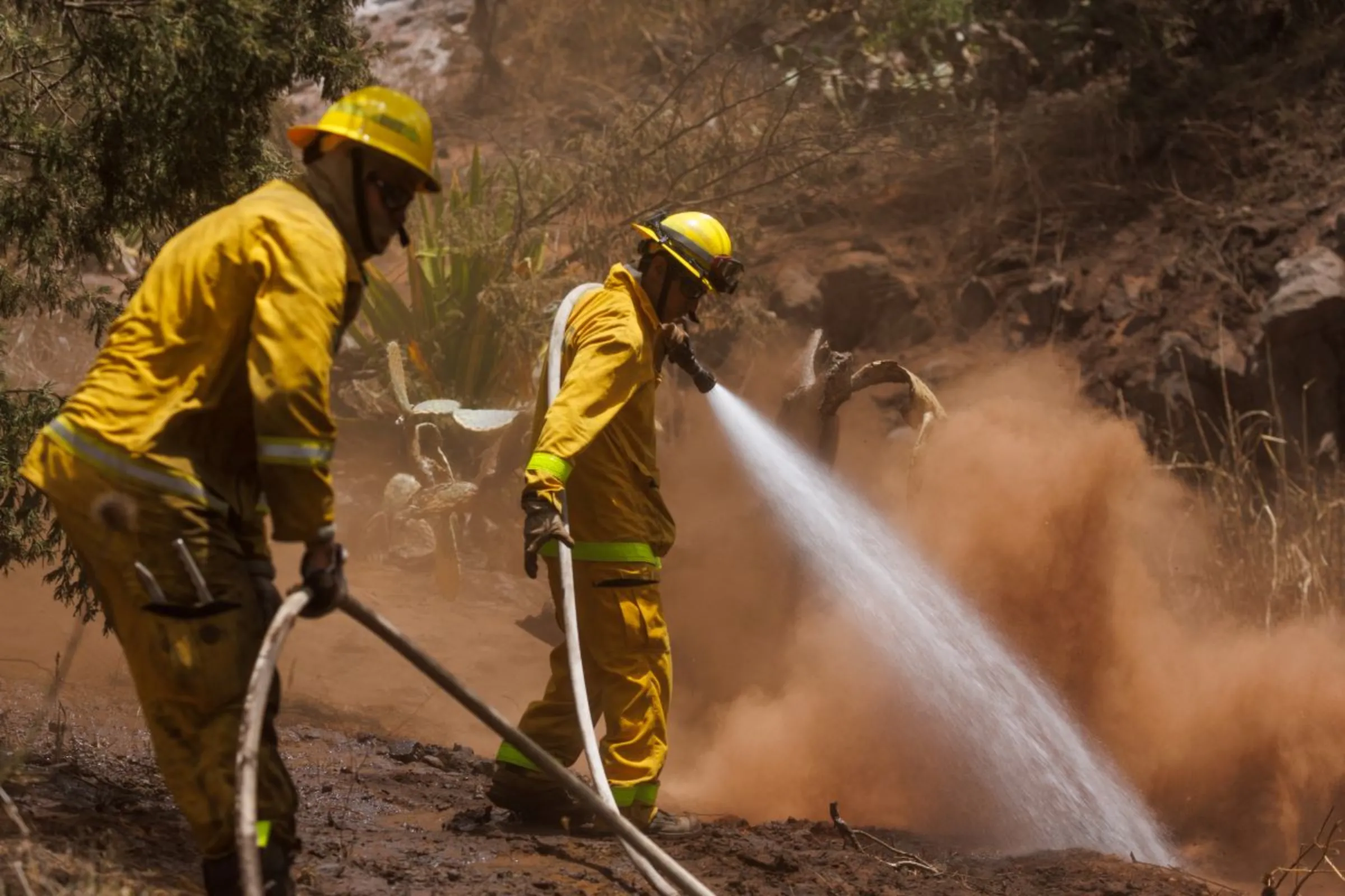 Maui County firefighters fight flare-up fires in a canyon in Kula on Maui island, Hawaii, U.S., August 13, 2023. REUTERS/Mike Blake