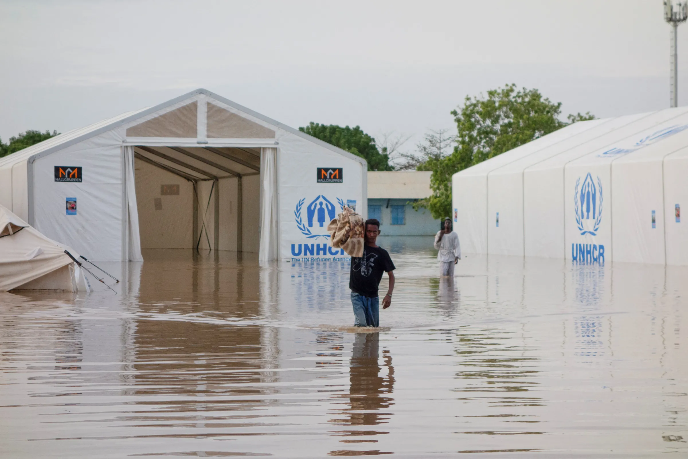 Displaced Sudanese men walk through a flooded street next to the UNHCR tents, following a heavy rainfall in Kassala, Sudan, July 26, 2024. REUTERS/Mohamed Abdulmajid