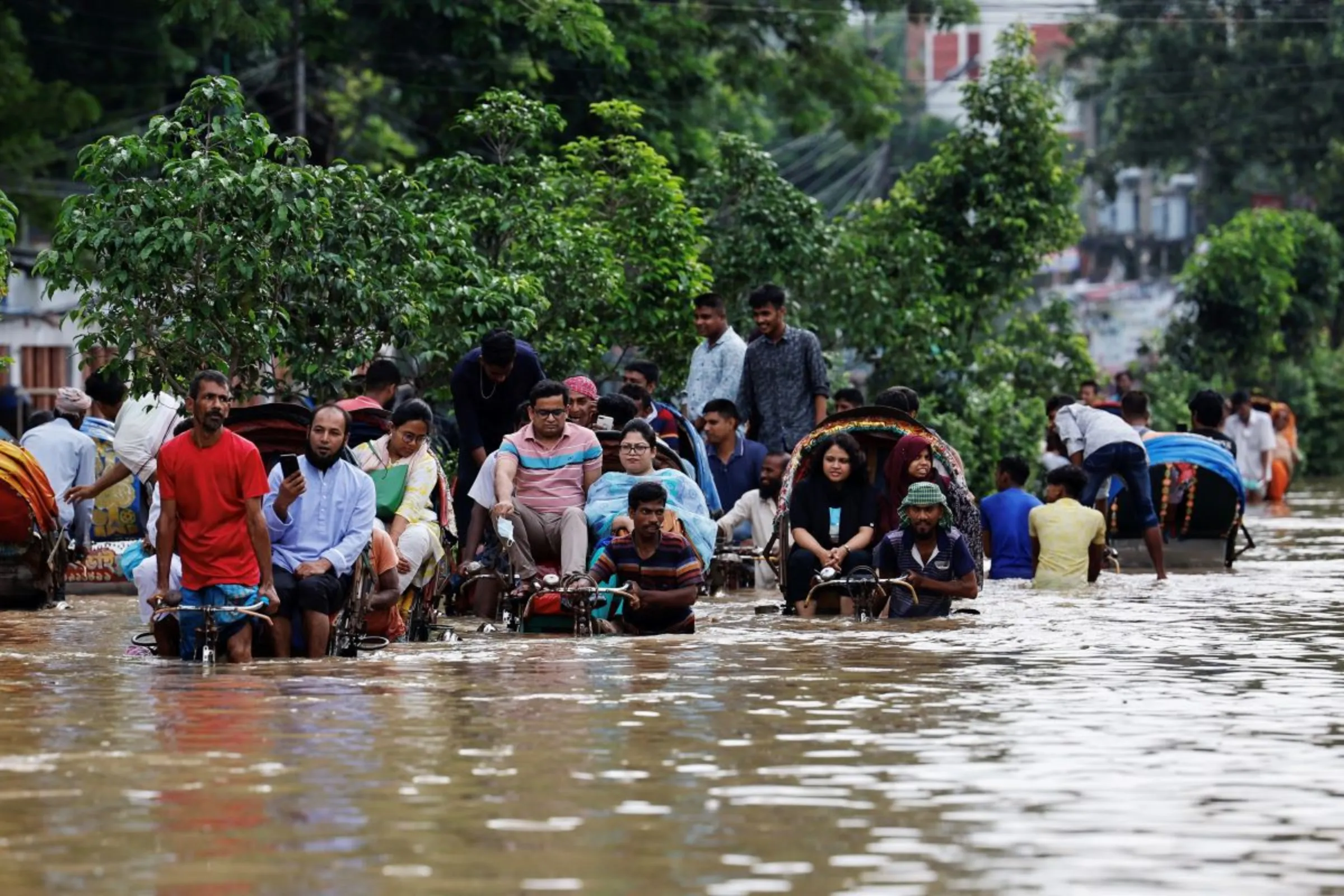 People move on rickshaws along a flooded street after a downpour in Dhaka, Bangladesh, July 12, 2024. REUTERS/Mohammad Ponir Hossain
