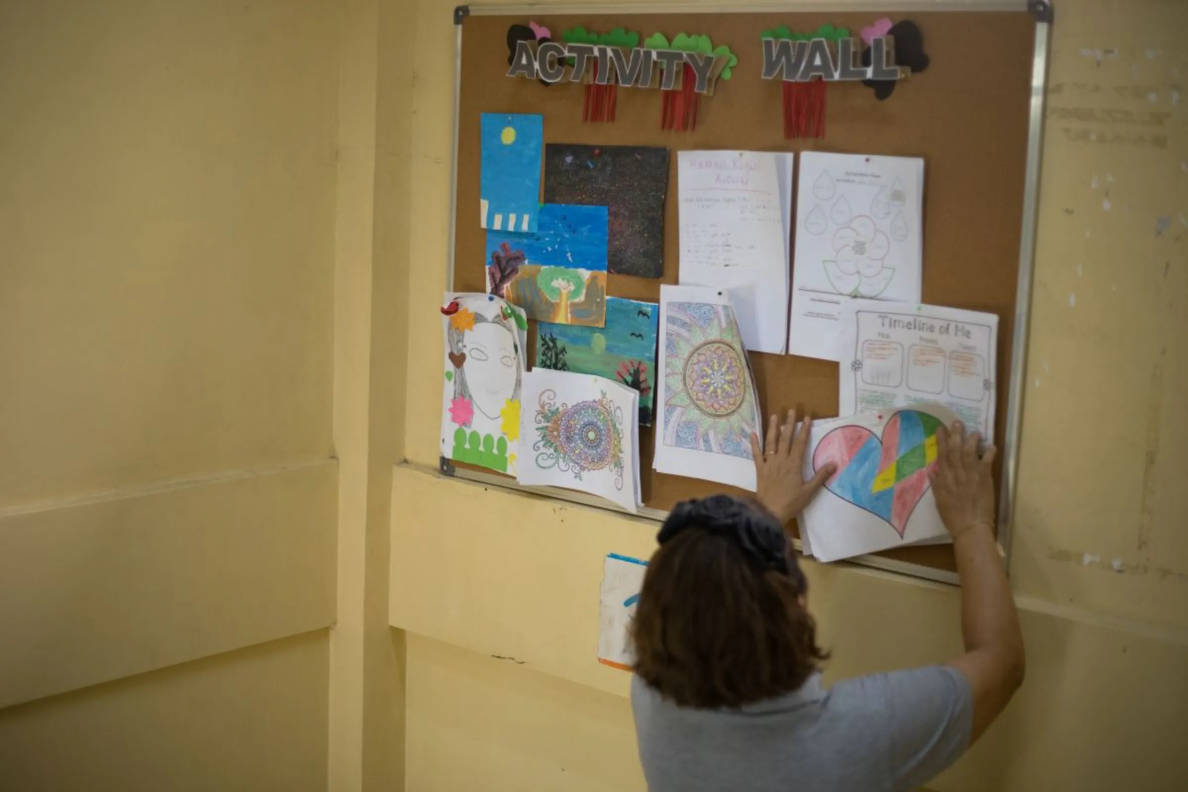 A staff of the Women and Children’s Shelter of Tacloban posts art works of girls and women rescued from sex trafficking and violence, Tacloban City, Philippines. October 9, 2023. Thomson Reuters Foundation/Kathleen Limayo