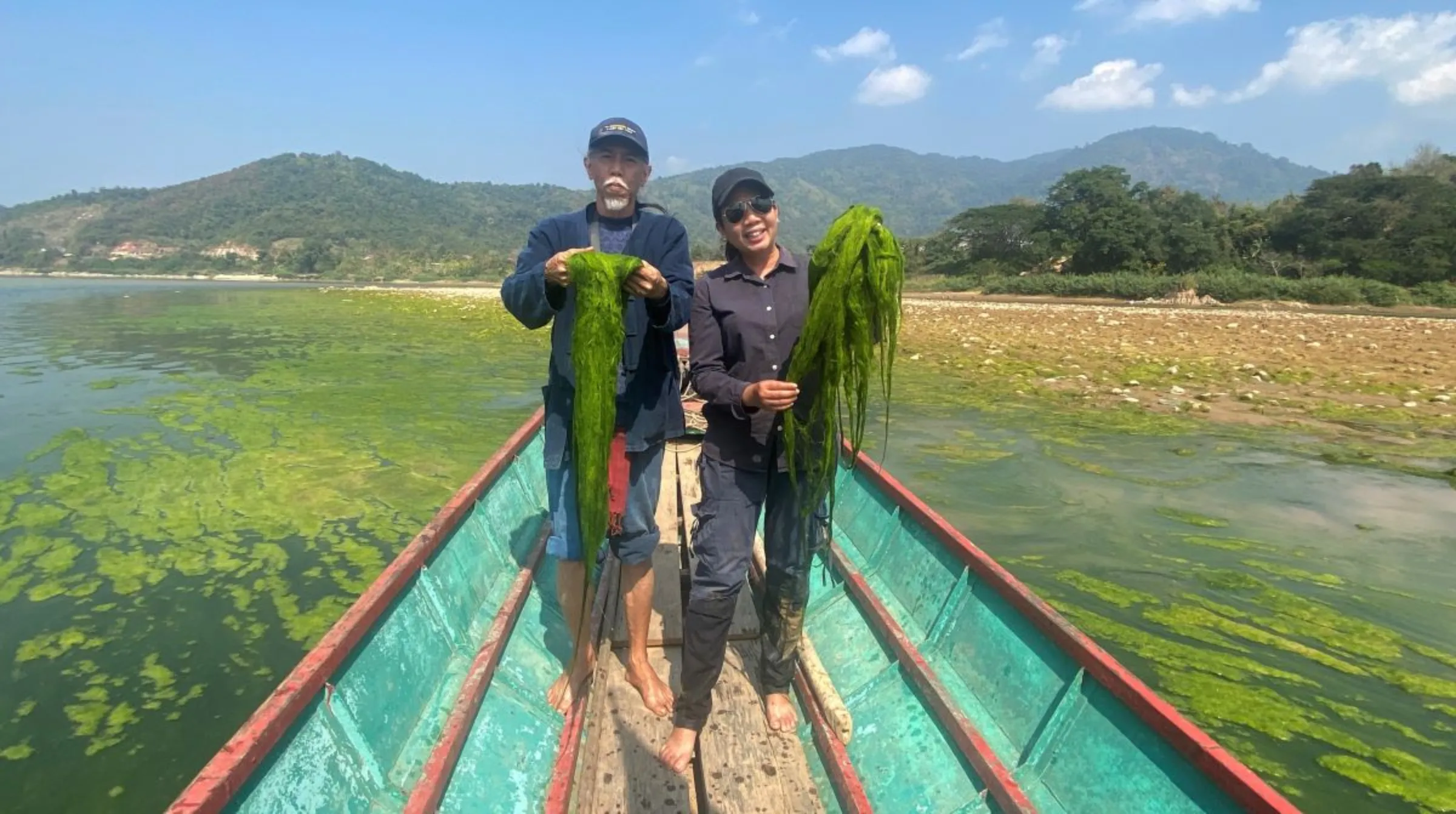 Conservationist Niwat Roykaew and Pianporn Deetes, campaign director for Thailand and Myanmar at Rivers International, hold river weed on a boat on the Mekong River on the Thai-Laos border. February 6, 2023. Thomson Reuters Foundation/Rina Chandran